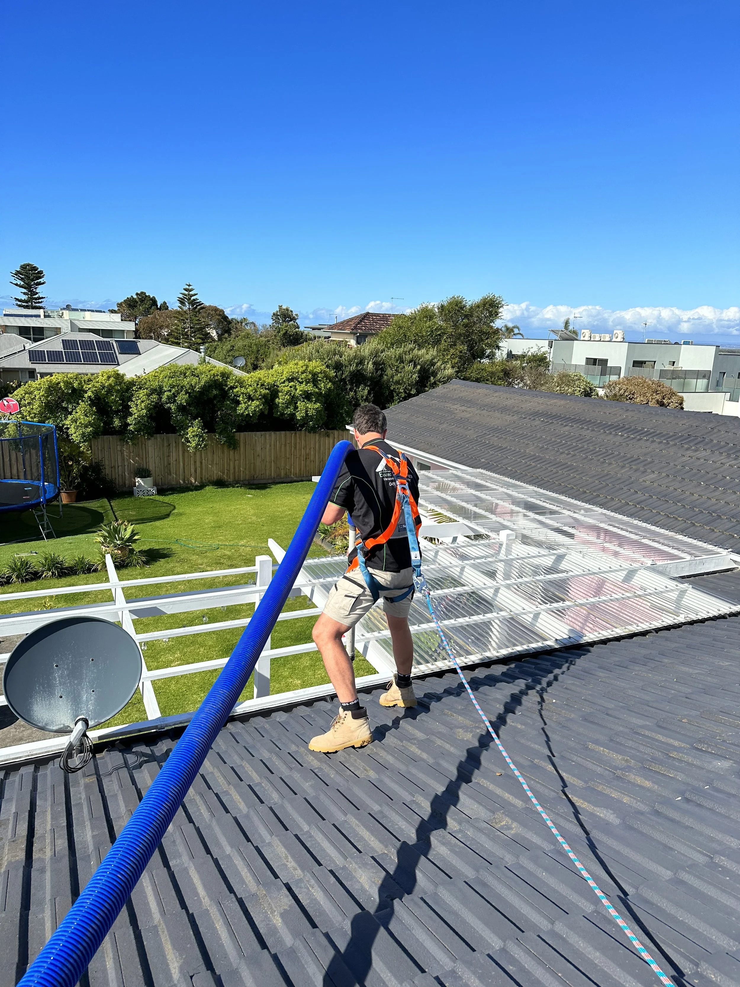 Geelong, Surf Coast and Bellarine Vacuum Gutter Cleaning. Man on roof in safety harness cleaning gutters.