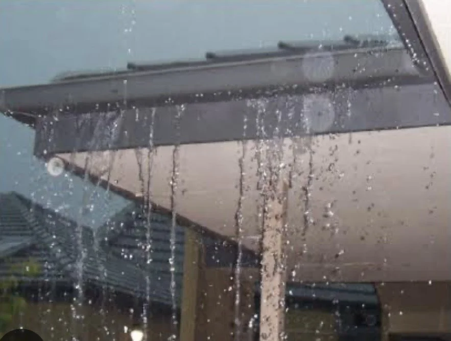 Rain and water overflowing from blocked gutters.