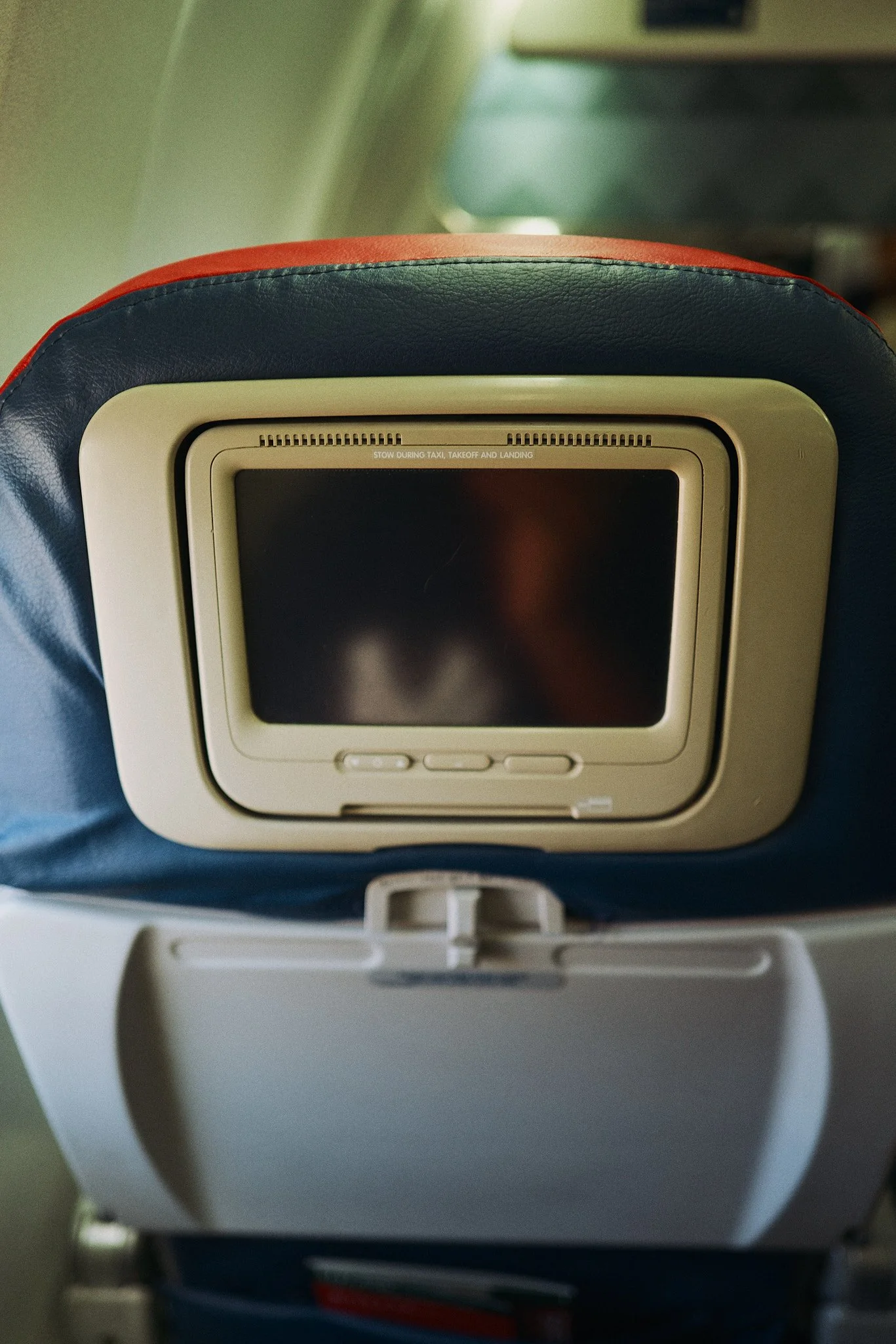 Old school Delta airplane seat back with a personal entertainment screen and control buttons, with a pocket below.