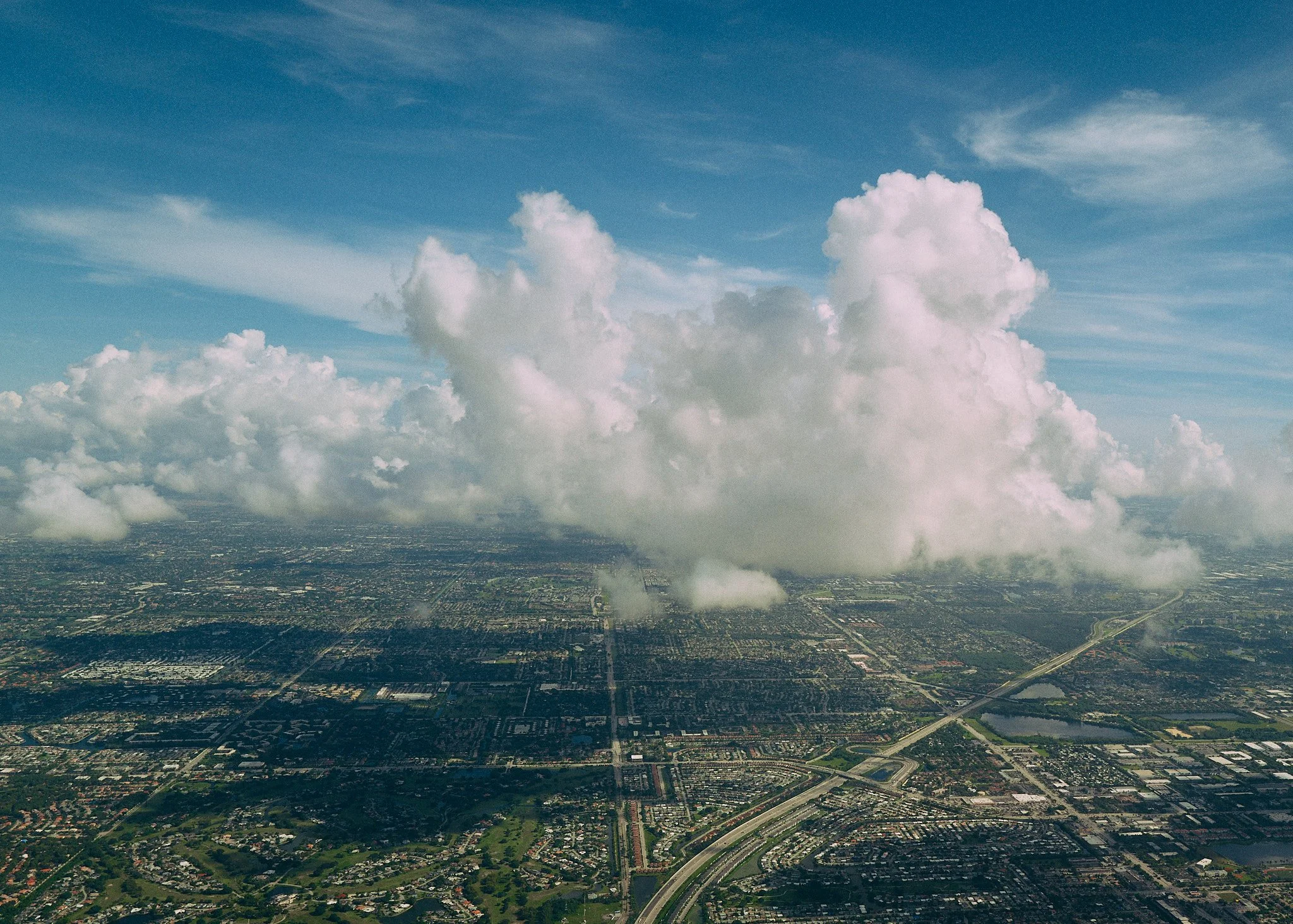 Aerial view of a cityscape with a large cloud formation in the sky.