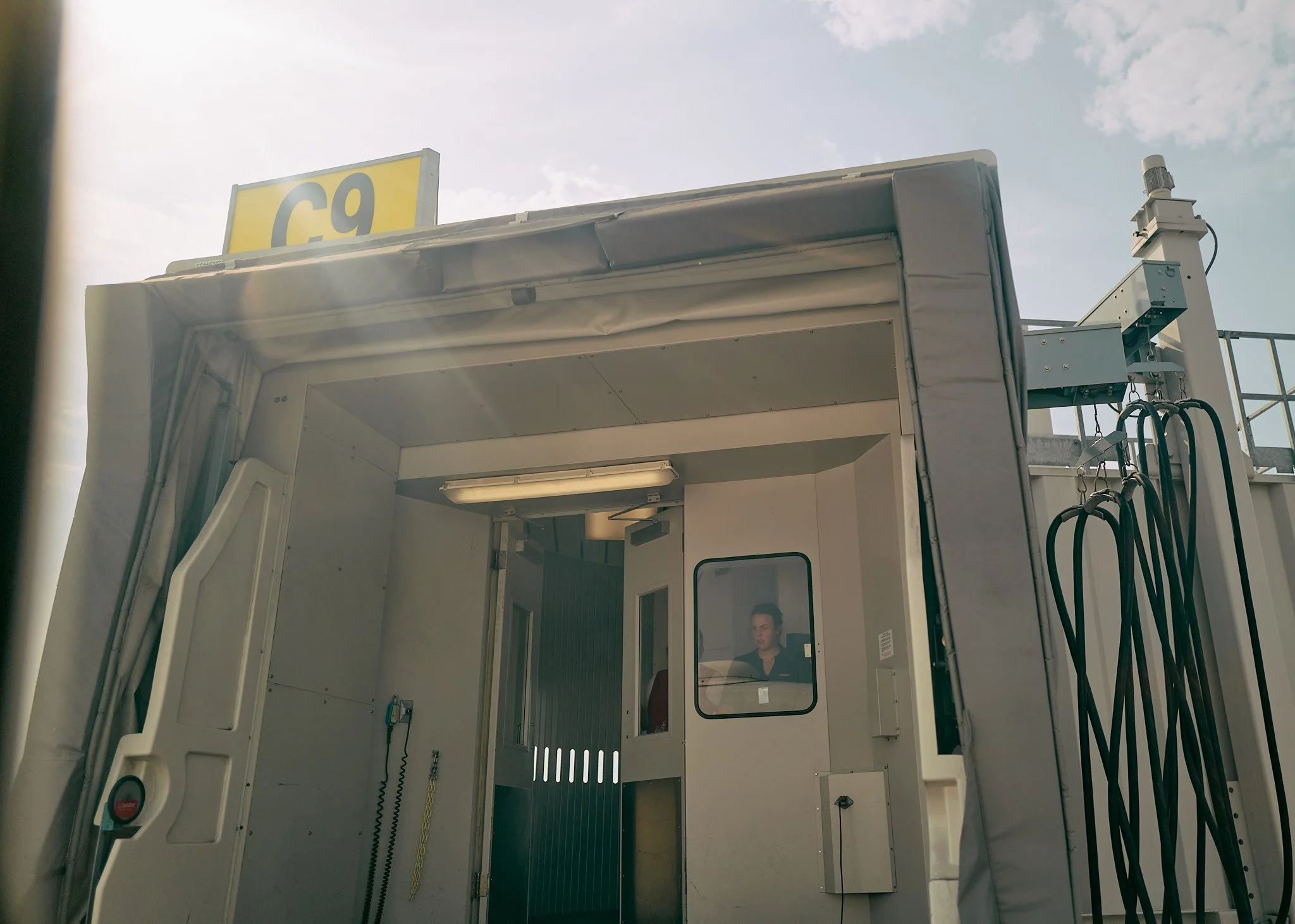 View of an airport jet bridge labeled 'C9' with a gate attendant in the booth, under a partly cloudy sky. photo by Matt Ellis