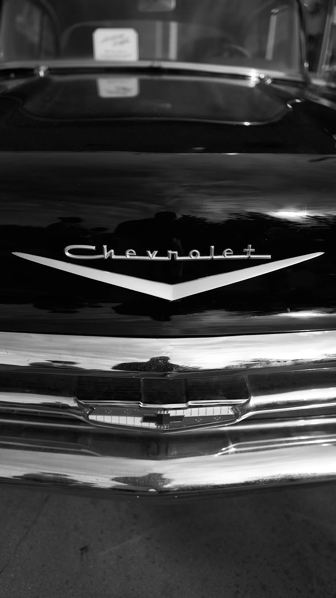 Close-up of the front of a vintage Chevrolet car, showing the Chevrolet emblem and grill in black and white.