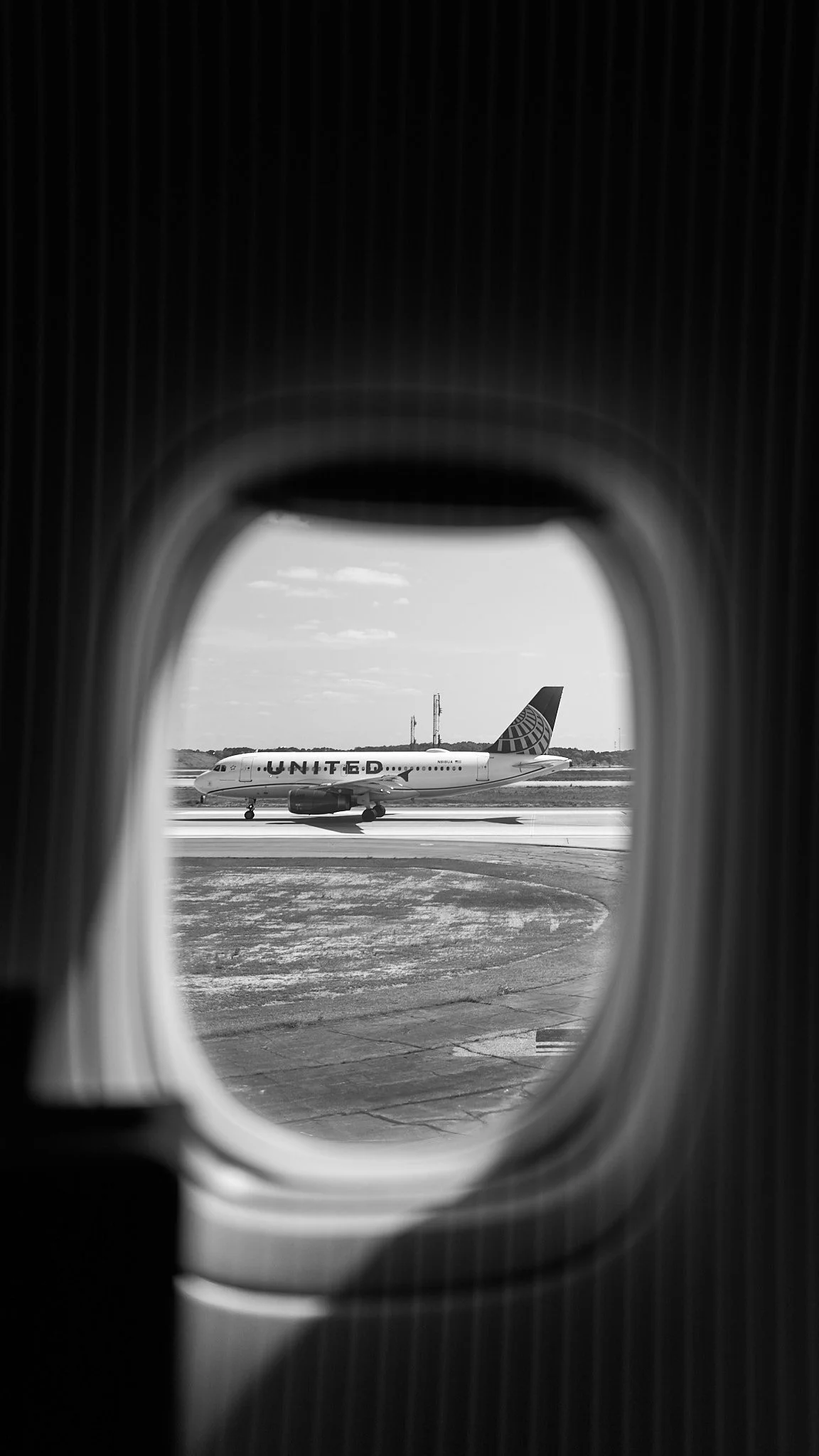 View of an airplane on the runway seen through an airplane window.