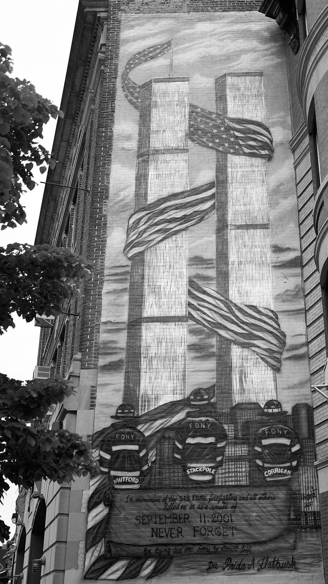 Murial on a building wall depicting the Twin Towers with American flags flowing around them and three firefighters' backpacks with their names, in memory of the 343 FDNY firefighters who died on September 11, 2001.