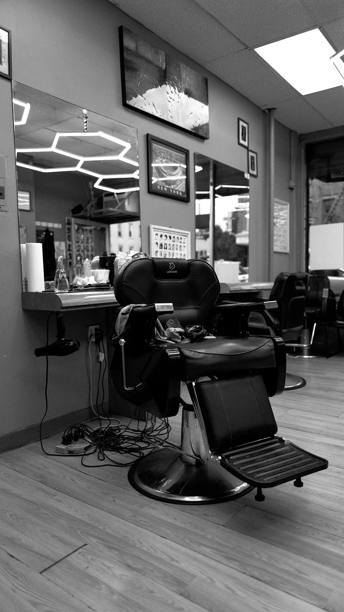 Empty barber's chair in a salon with framed pictures and mirrors on the wall.