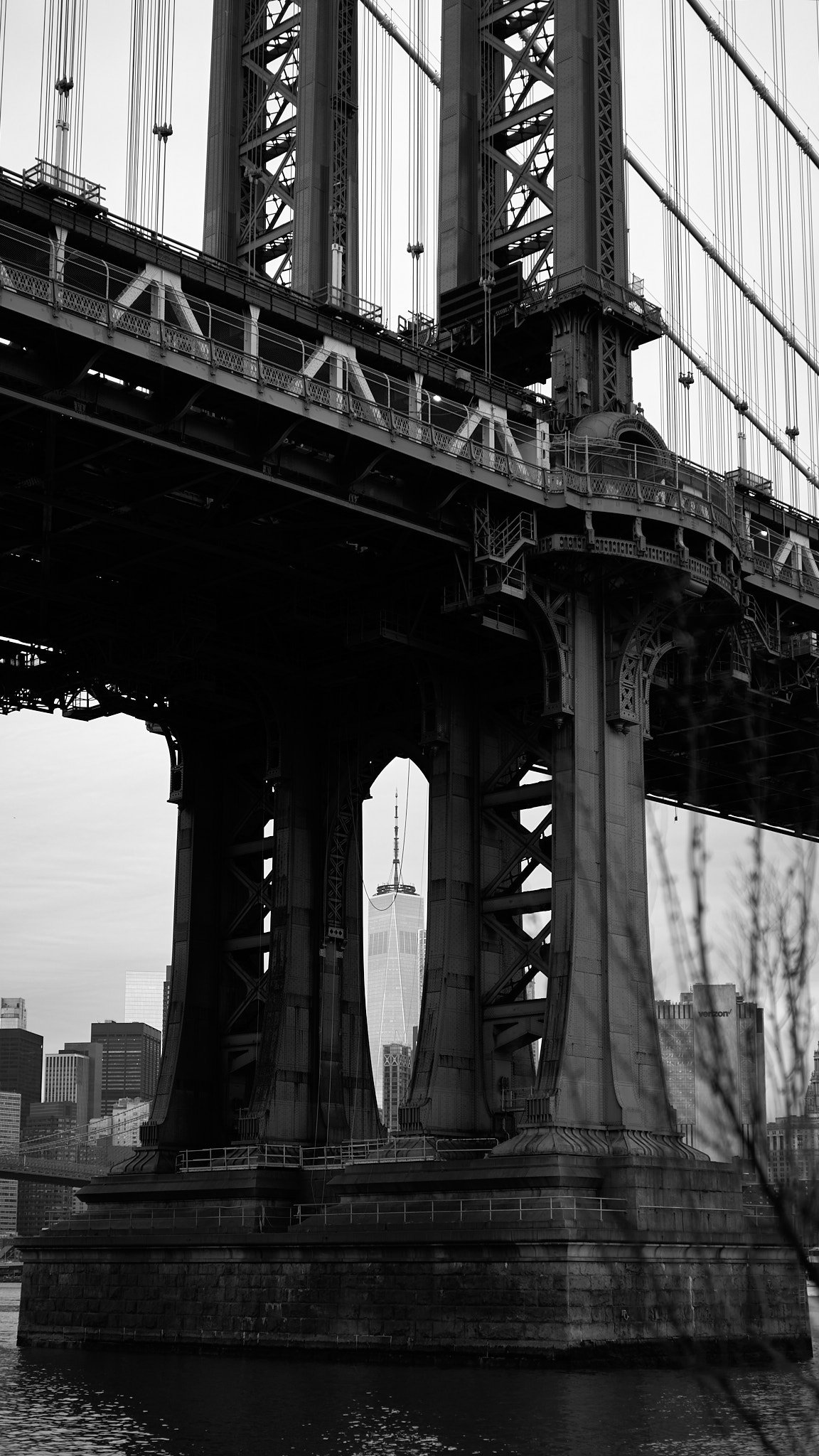 Black and white photo of the Brooklyn Bridge with the One World Trade Center in the background in New York City.
