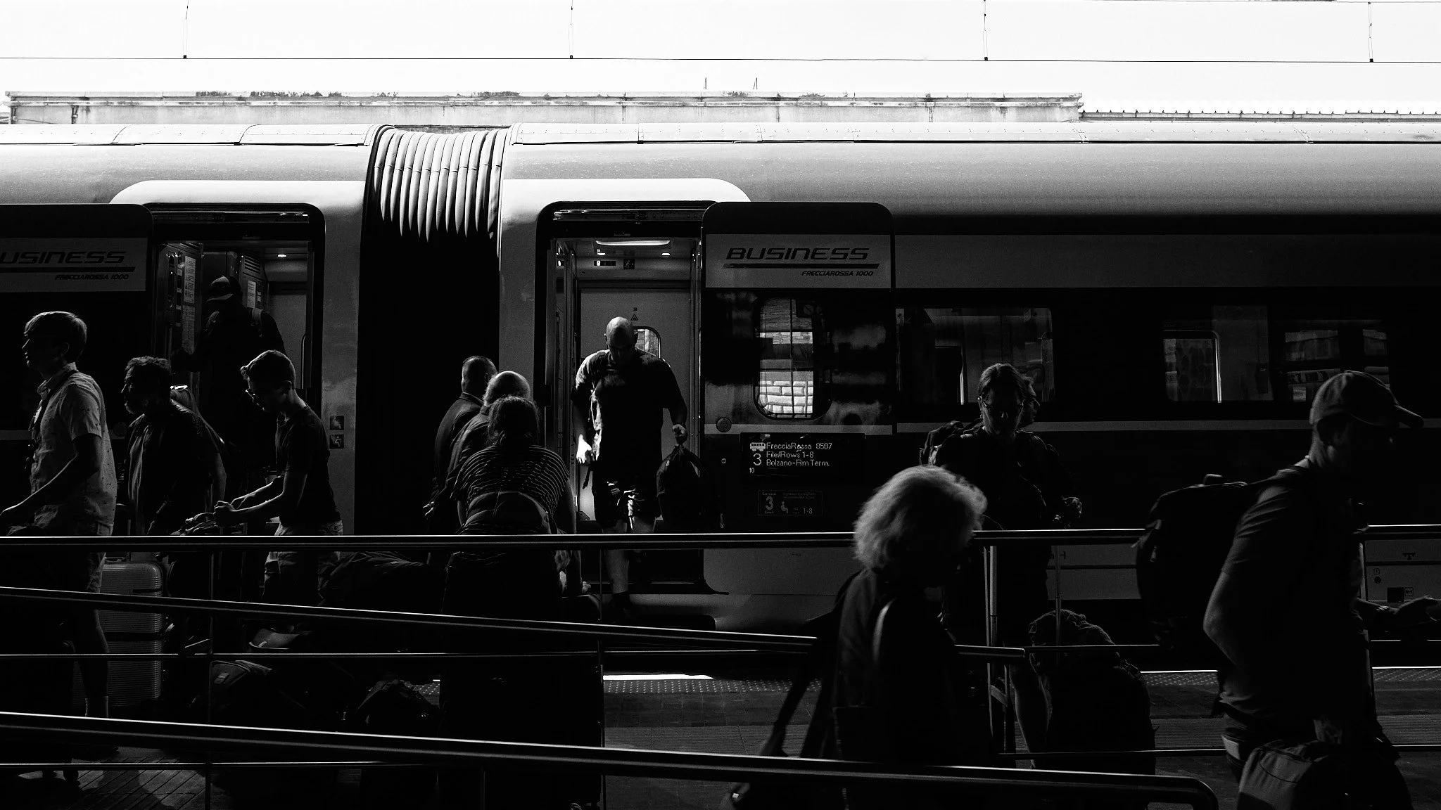 People boarding and exiting a modern train at a train station.