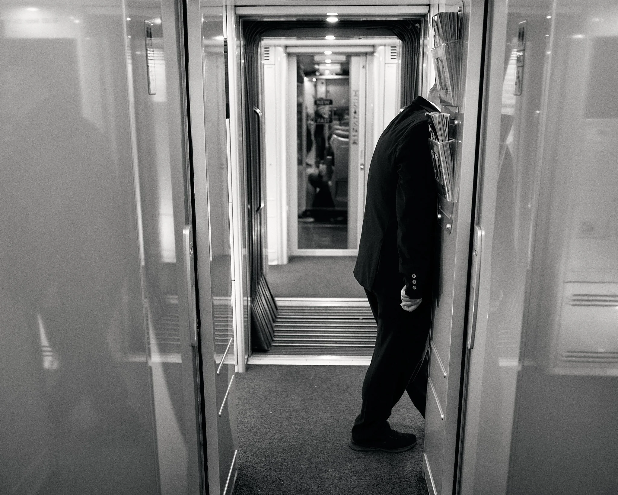 A man in a business suit bent over with his head against the wall in an airport hallway.