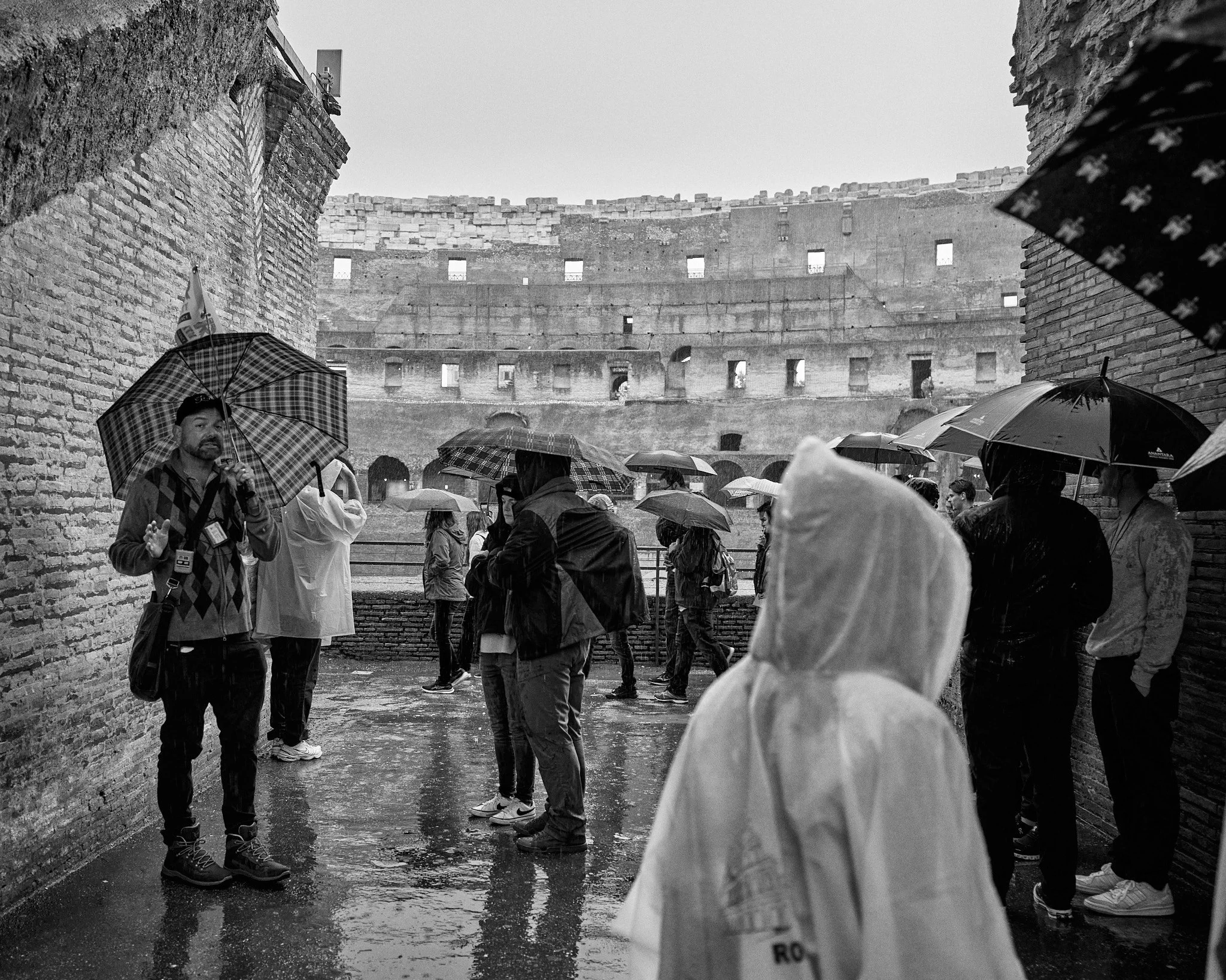 People standing with umbrellas in rain near the Colosseum in Rome, Italy.