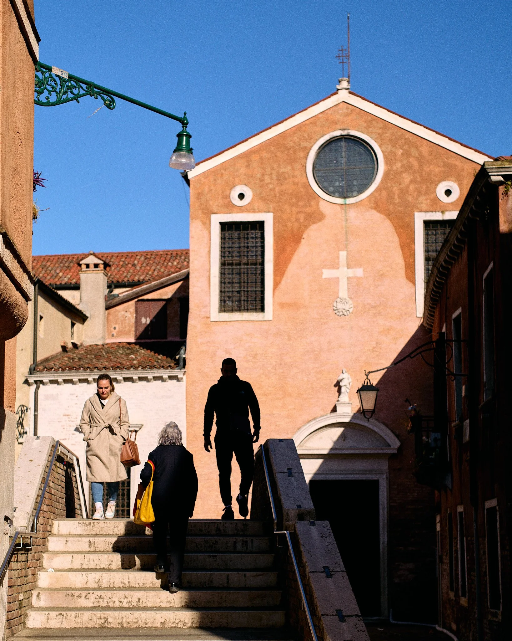 People walking up stairs outside a church building with a large cross and religious symbols painted on the facade.