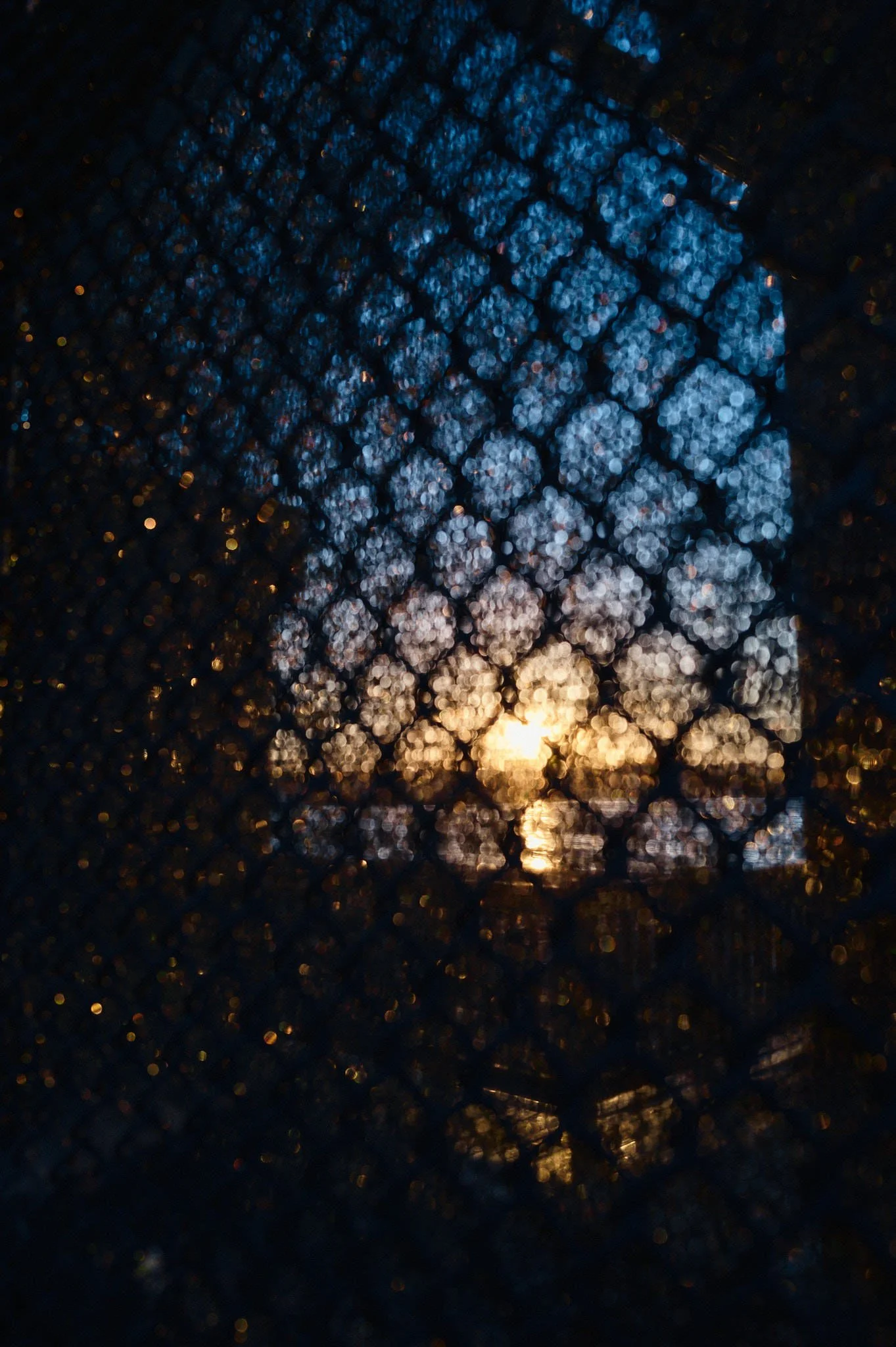 Sunset view through rain-covered glass with reflections and bokeh effect.