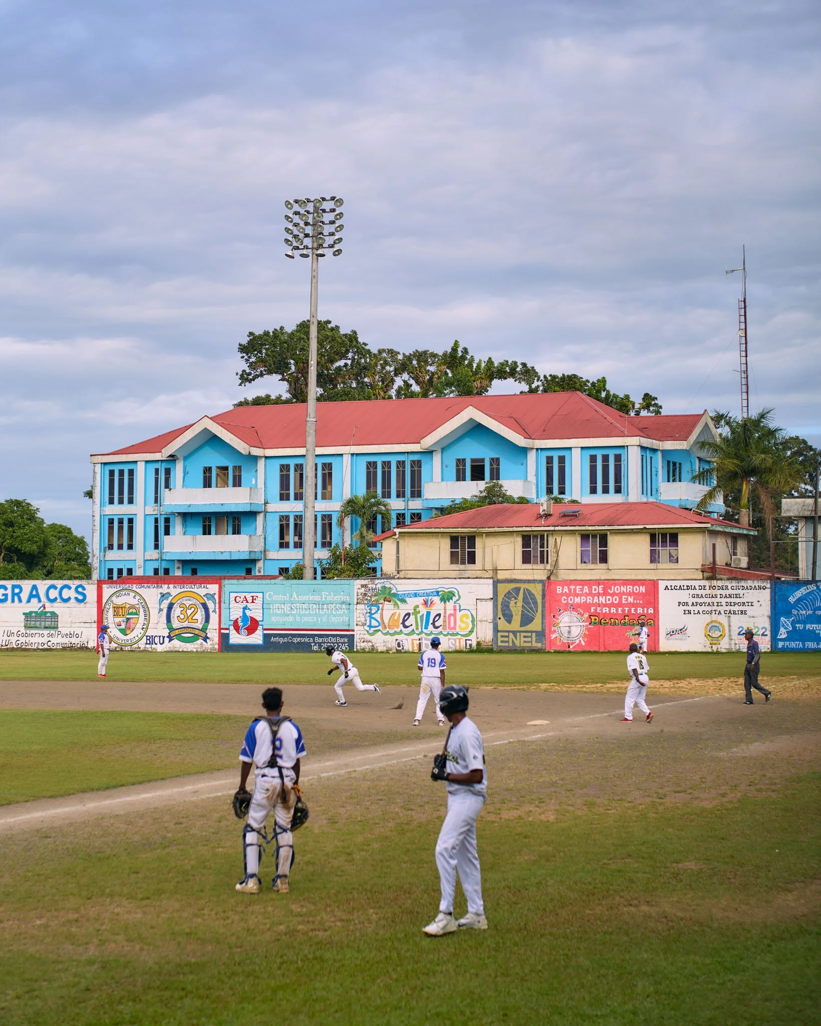 Baseball game with players on the field and spectators in the background in a small town.