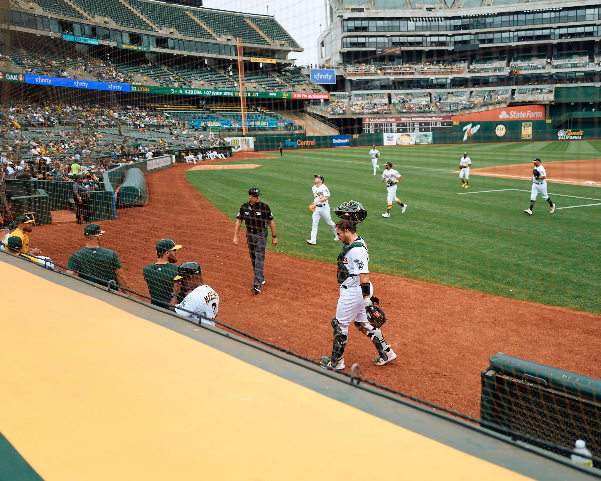 Baseball players on the field and in the dugout during a game at a stadium with spectators in the stands.