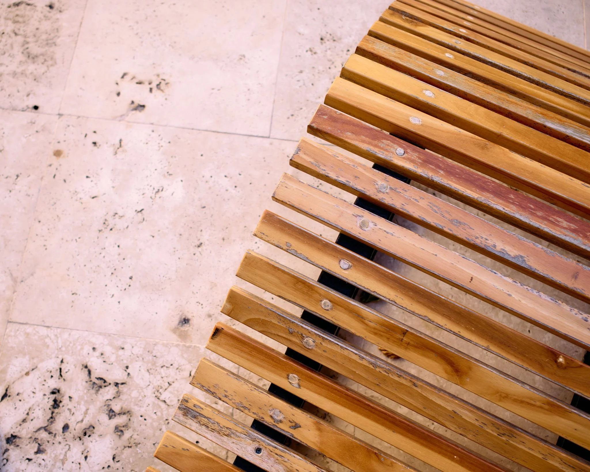 Close-up of a wooden slatted bench on a stone patio surface.