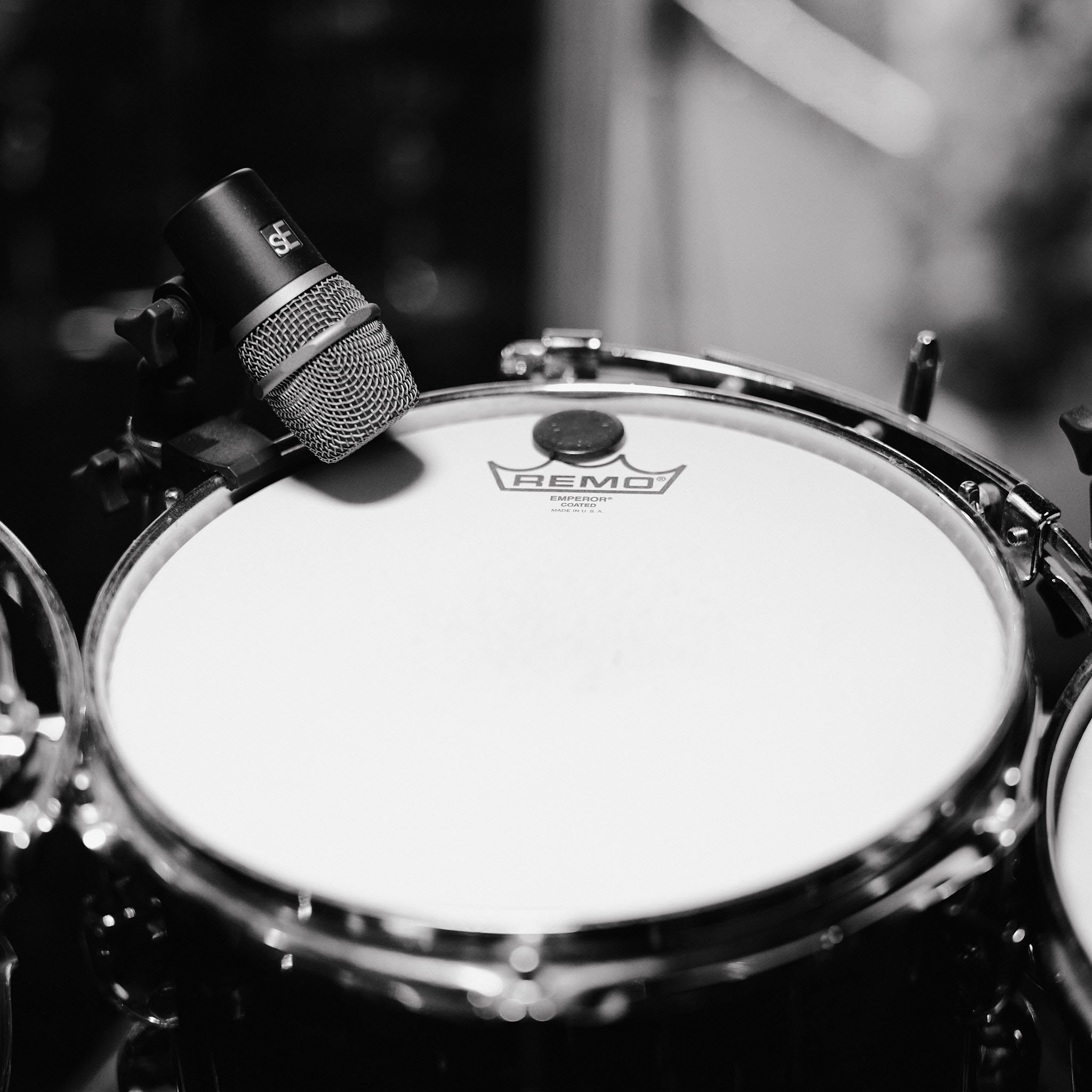 Close-up of a drum with a microphone positioned above it, black and white photograph.