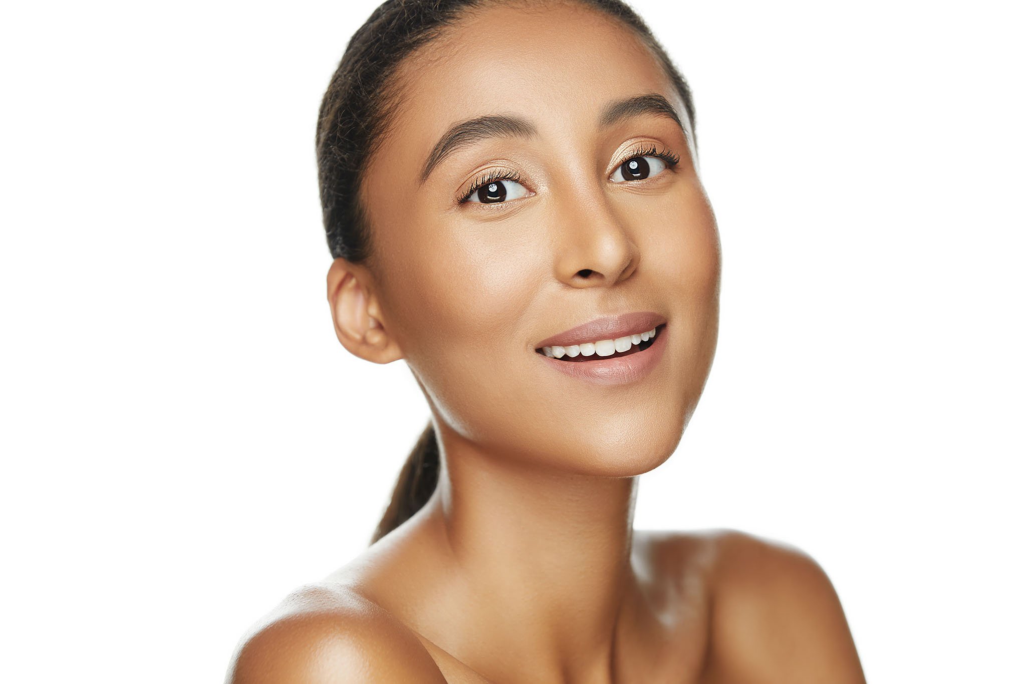 Close-up of a smiling woman with smooth skin and natural makeup, with shoulders Bare, against a plain white background.