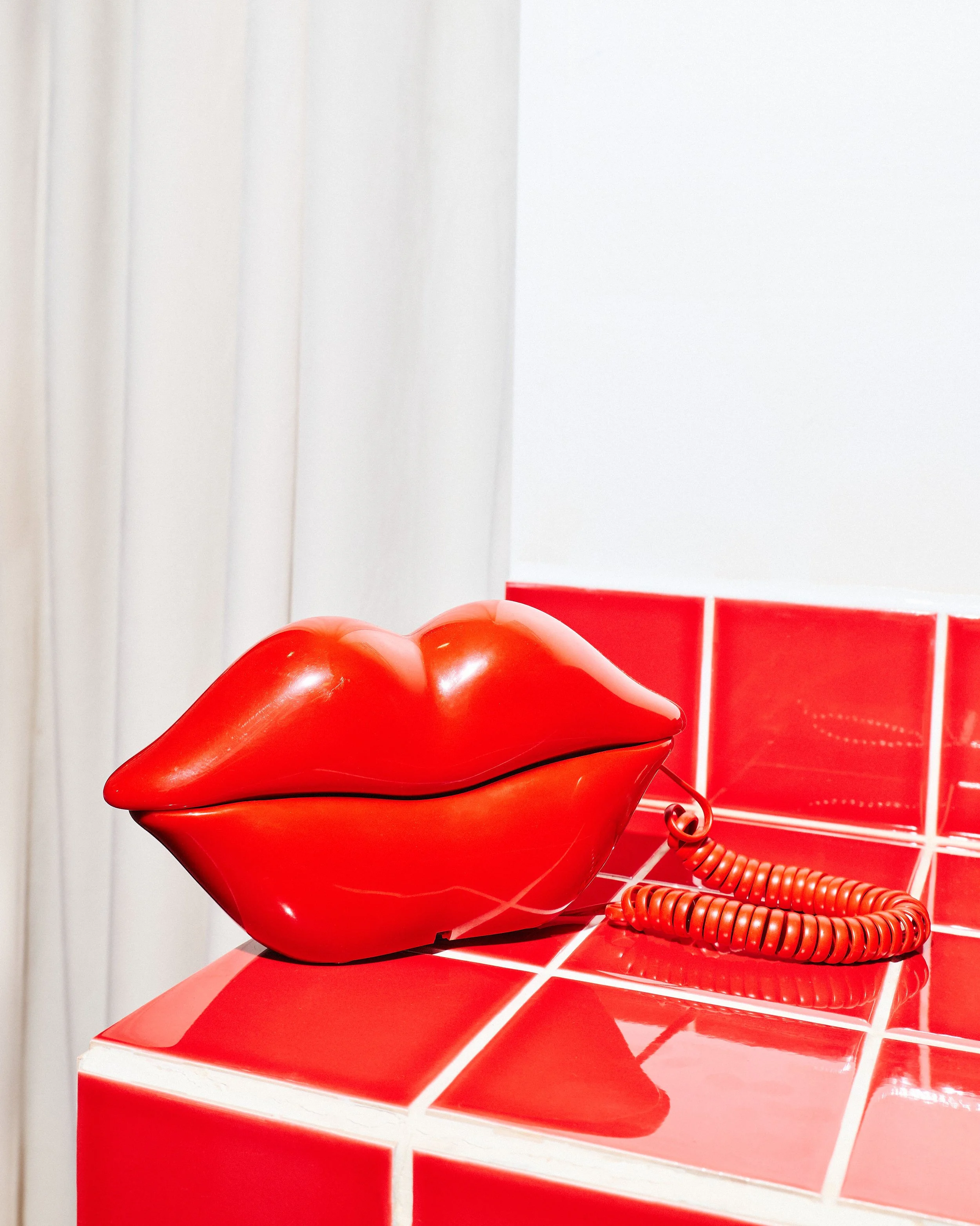 Sculptural red lips telephone displayed on a glossy red tiled counter inside Kill! Kill! Coffee.
