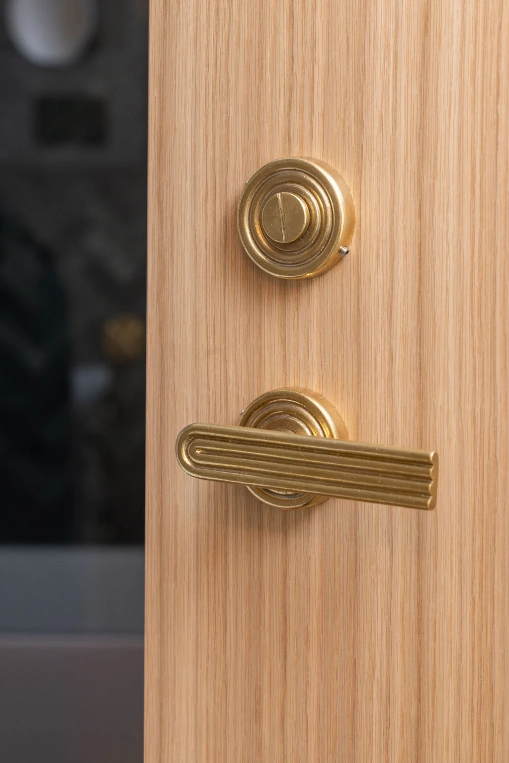 Ribbed brass door handle mounted on a natural light oak door.