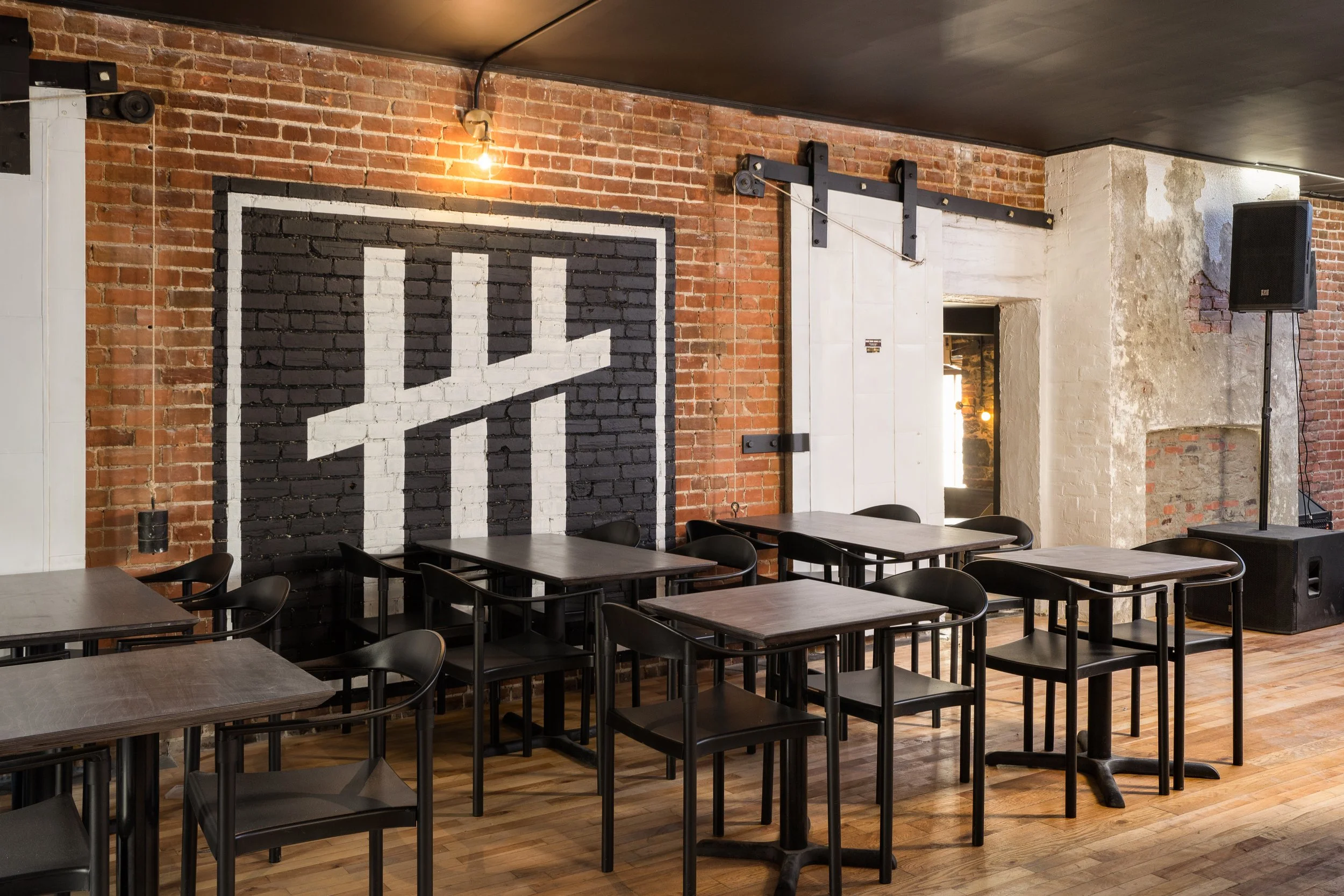 Exposed brick feature wall with bold black-and-white graphic and industrial sliding door hardware at Turbo Haüs.