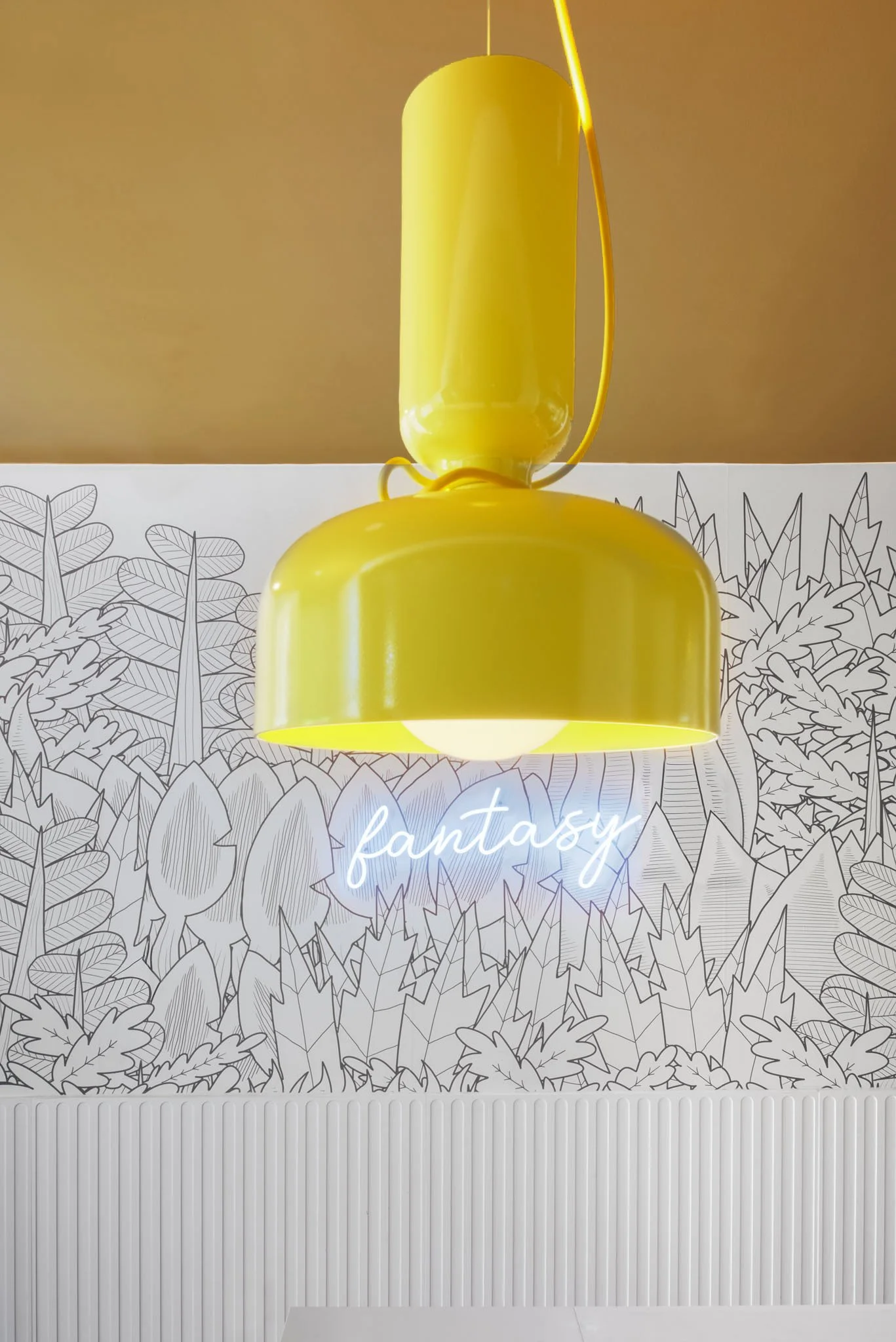 Bright yellow pendant light above a black-and-white botanical illustrated wall, glowing fantasy sign and white fluted panelling.