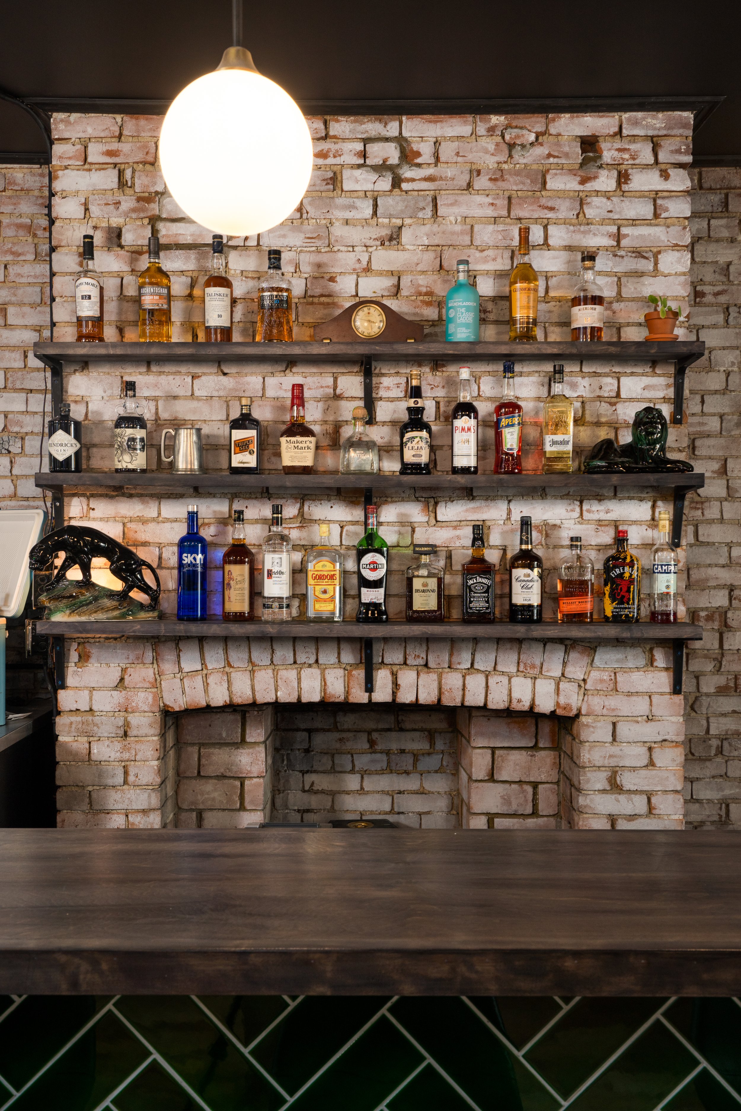 Liquor bottles displayed on dark wood shelves against an exposed whitewashed brick wall at Turbo Haüs.