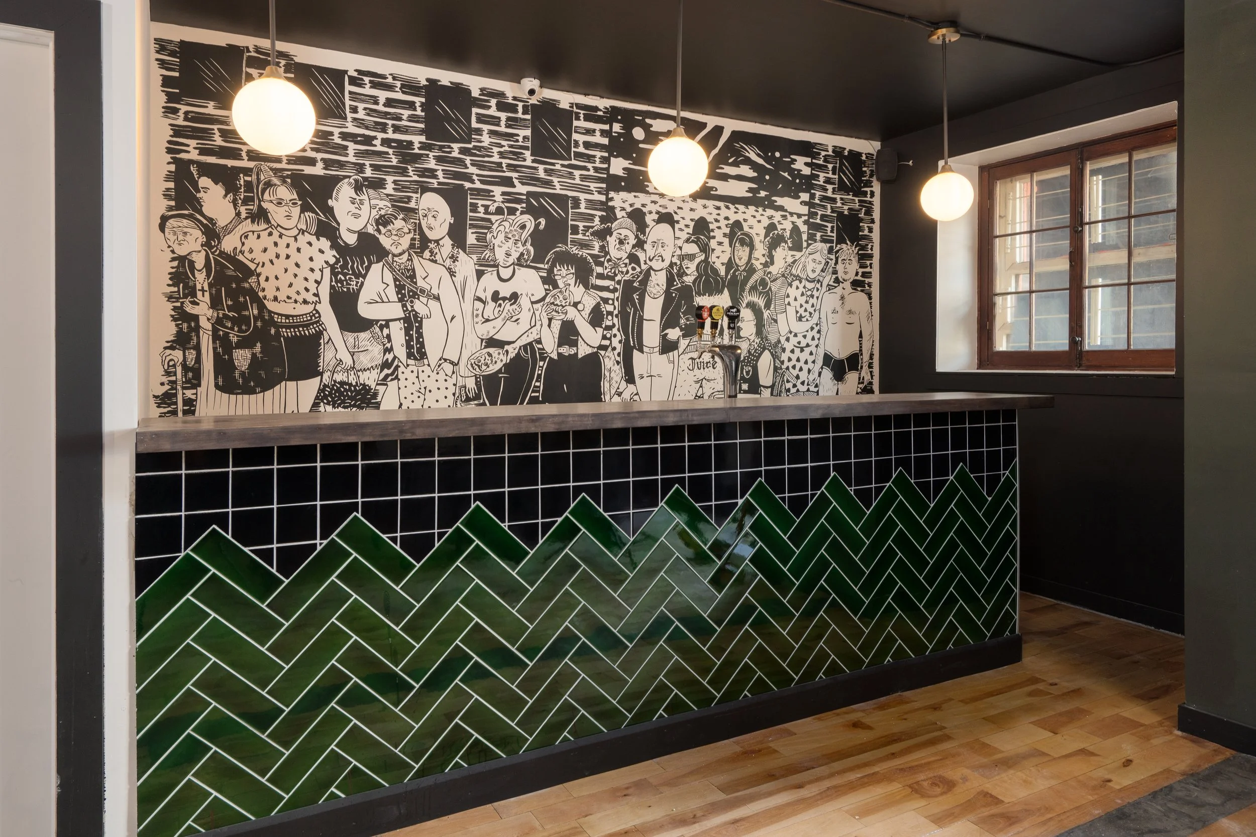 Black-and-white illustrated mural above dark wood seating, illuminated by globe pendants in the Turbo Haüs interior.