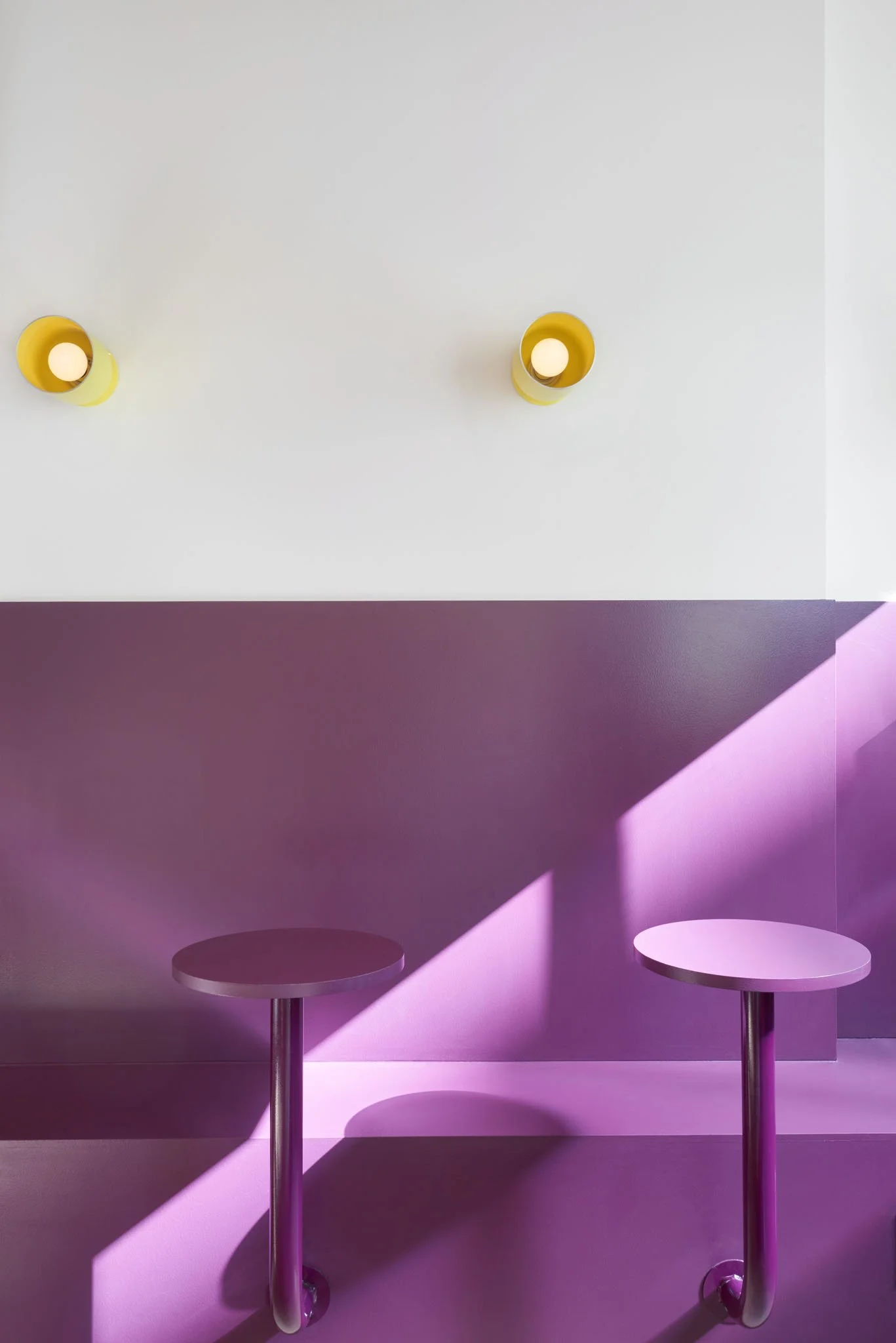 Fantasy Kitchen café seating area with plum purple walls, matching round tables, built-in bench and yellow wall lights.