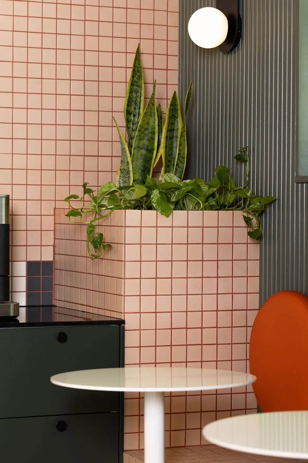 Farmhouse Creative Labs office lounge with pink tile, orange seating and globe sconces