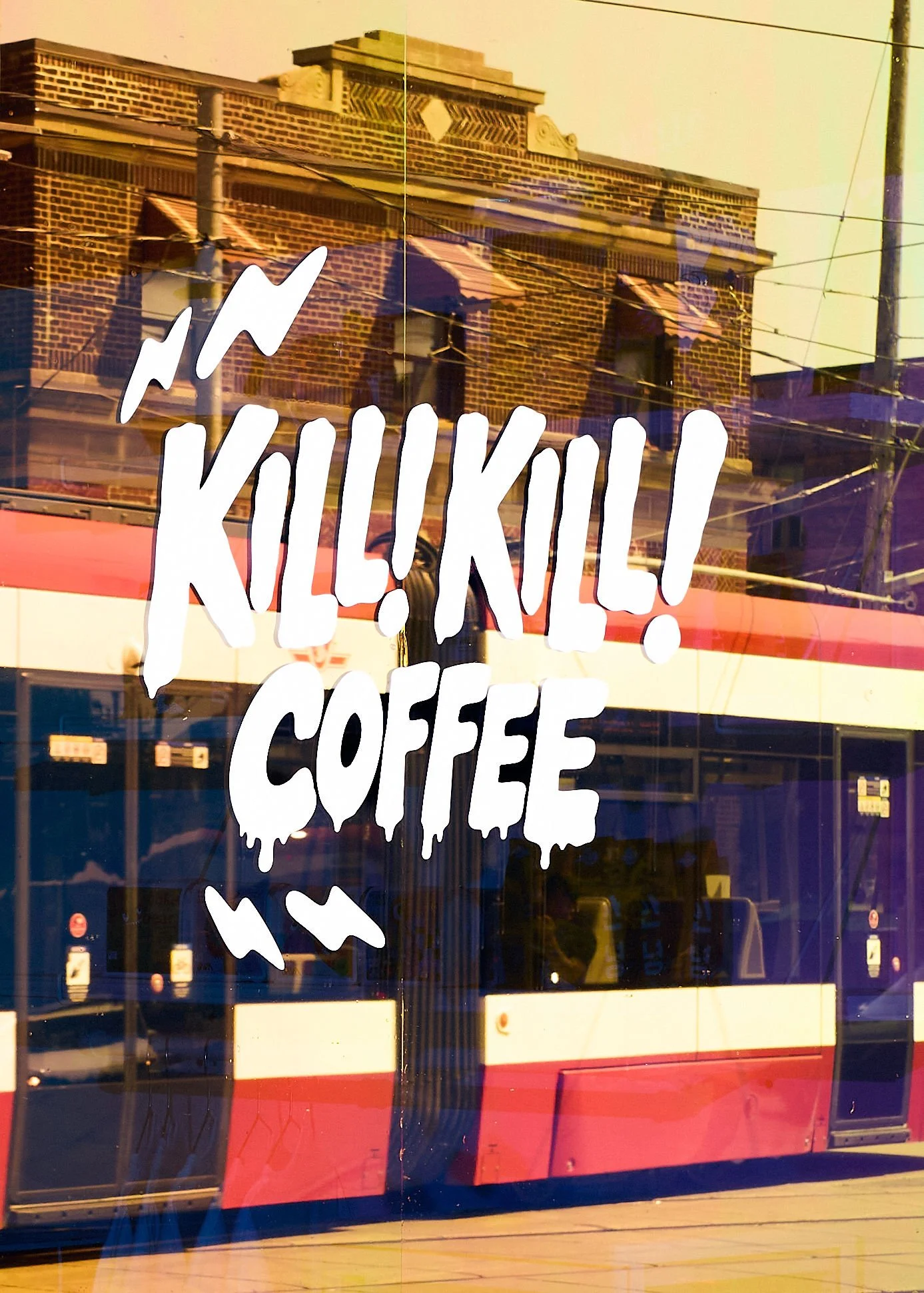 Large white Kill! Kill! Coffee illustrated logo applied to the café's front window in Toronto.