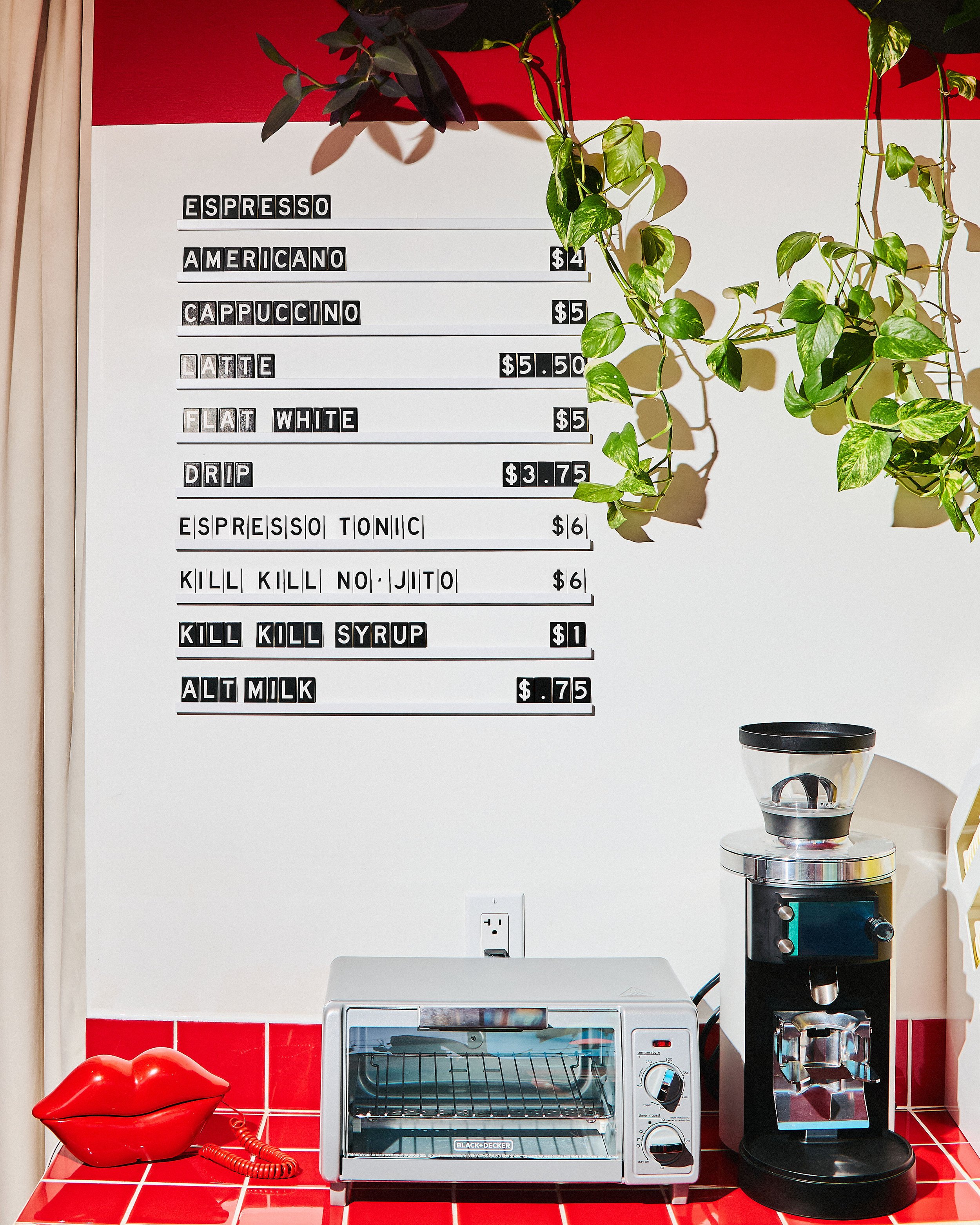 Kill! Kill! Coffee café interior featuring a black-and-white menu board, red tiled counter, coffee grinder and hanging plants.