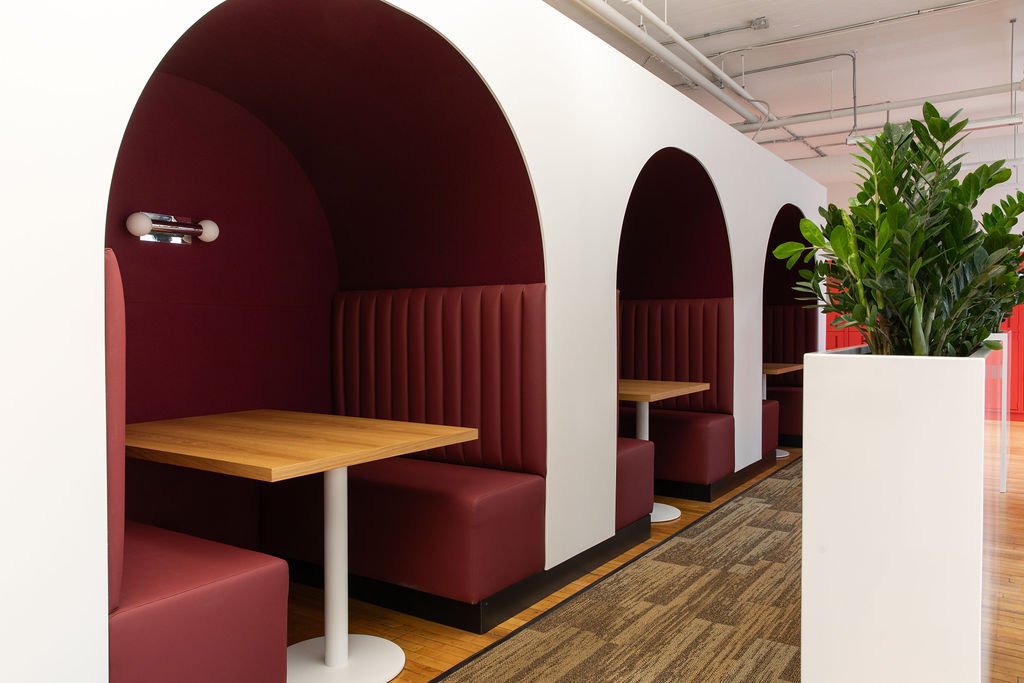 Built-in meeting booths at the Chef's Plate Toronto office, designed by Flodström Interiors, featuring burgundy upholstered banquettes, arched alcoves and light wood tables.
