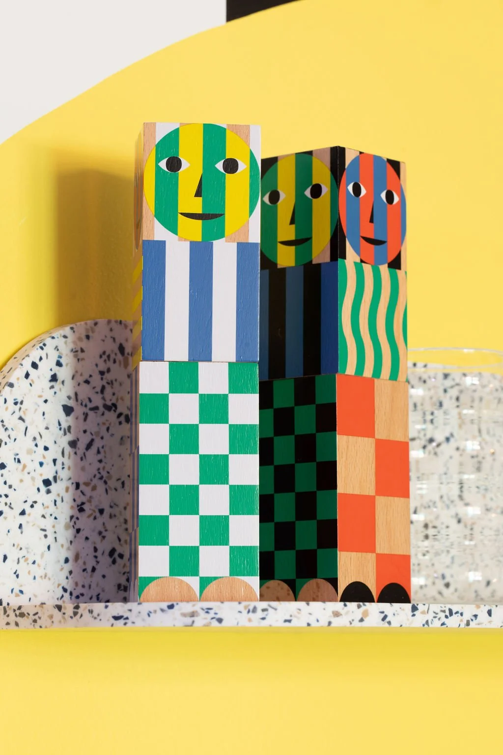Colourful geometric wooden figures displayed against a bright yellow wall in Flodström's creative studio.