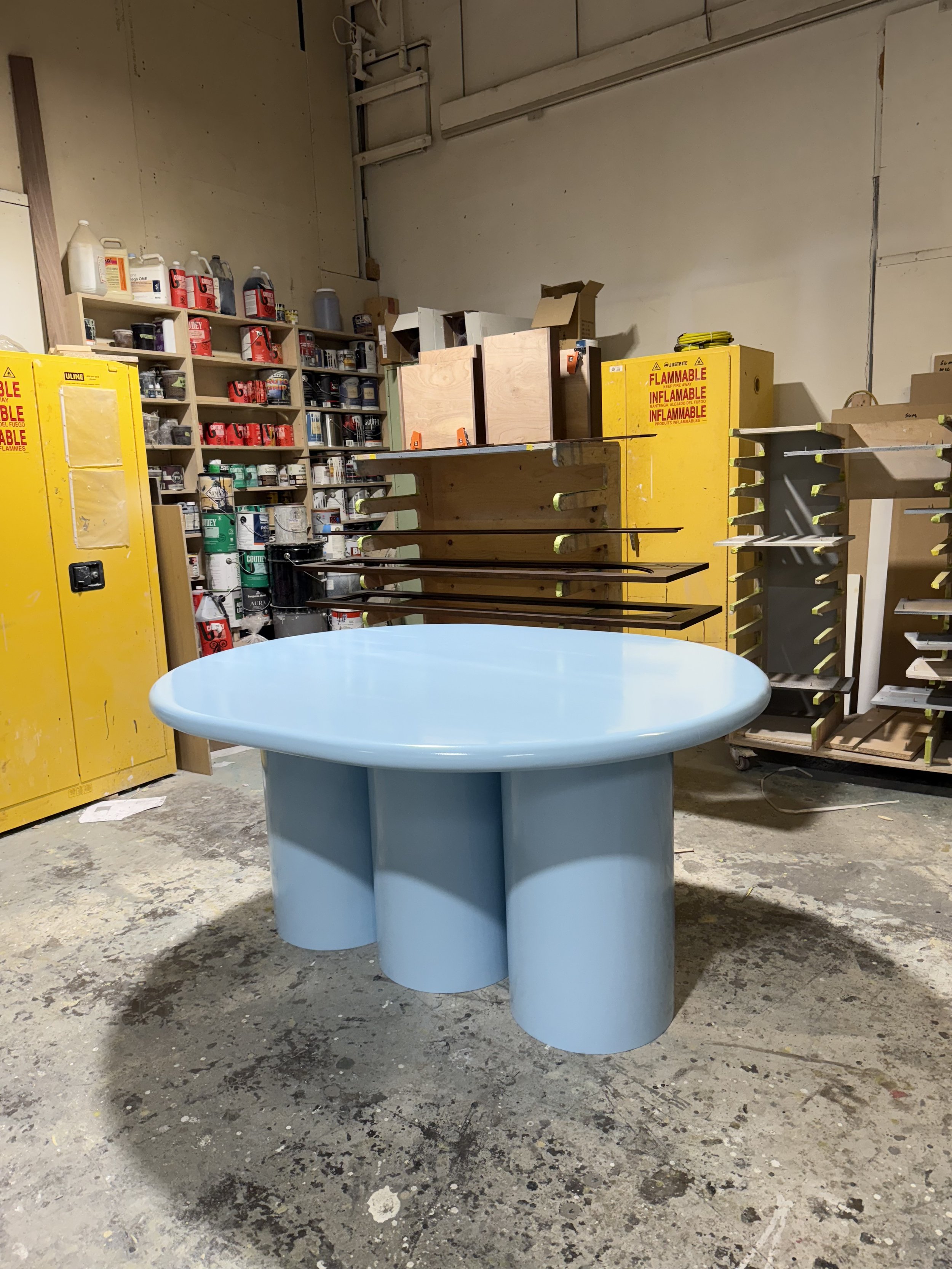 Custom blue breakfast table designed by Flodström Interiors for a residential kitchen, featuring a sculptural rounded triangular tabletop and cylindrical pedestal legs.