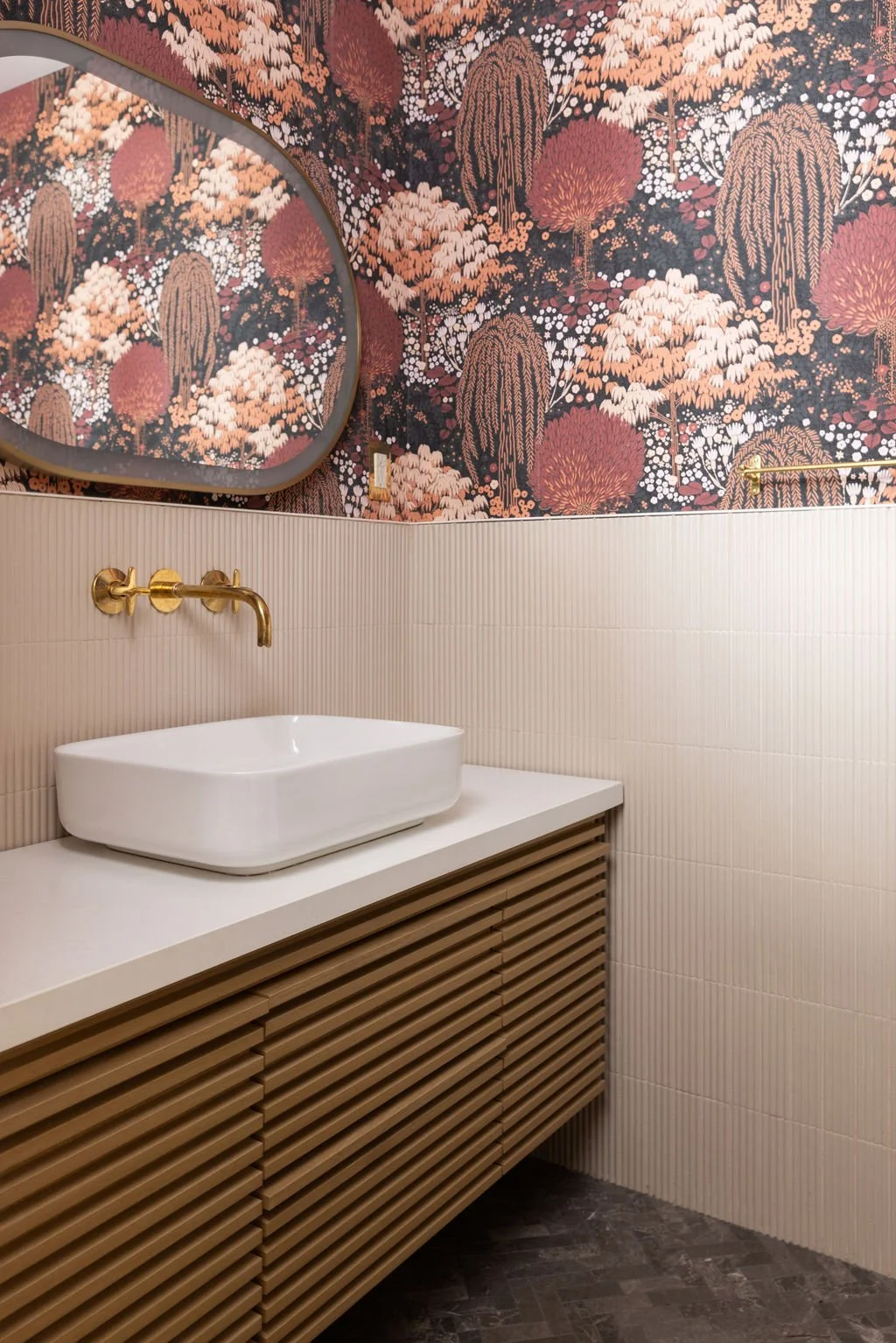 Toronto residential powder room featuring botanical wallpaper in warm pink and rust tones, a white vessel sink and slatted wood vanity.