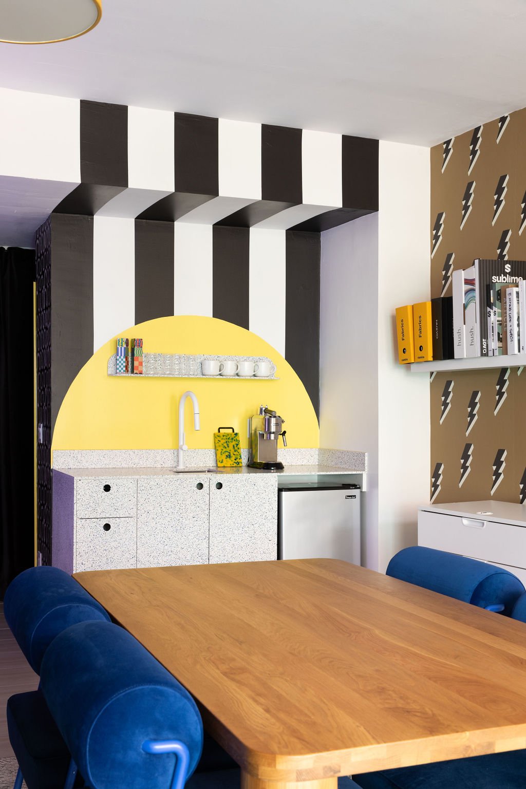 Black-and-white striped walls frame a bright yellow kitchenette with terrazzo-style cabinetry in Flodström's Toronto studio.