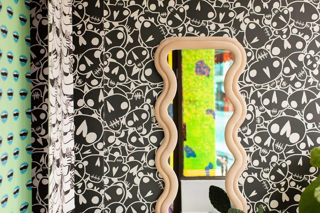 Close-up of black-and-white illustrated wallpaper and an organically shaped mirror at Flodström Studio.