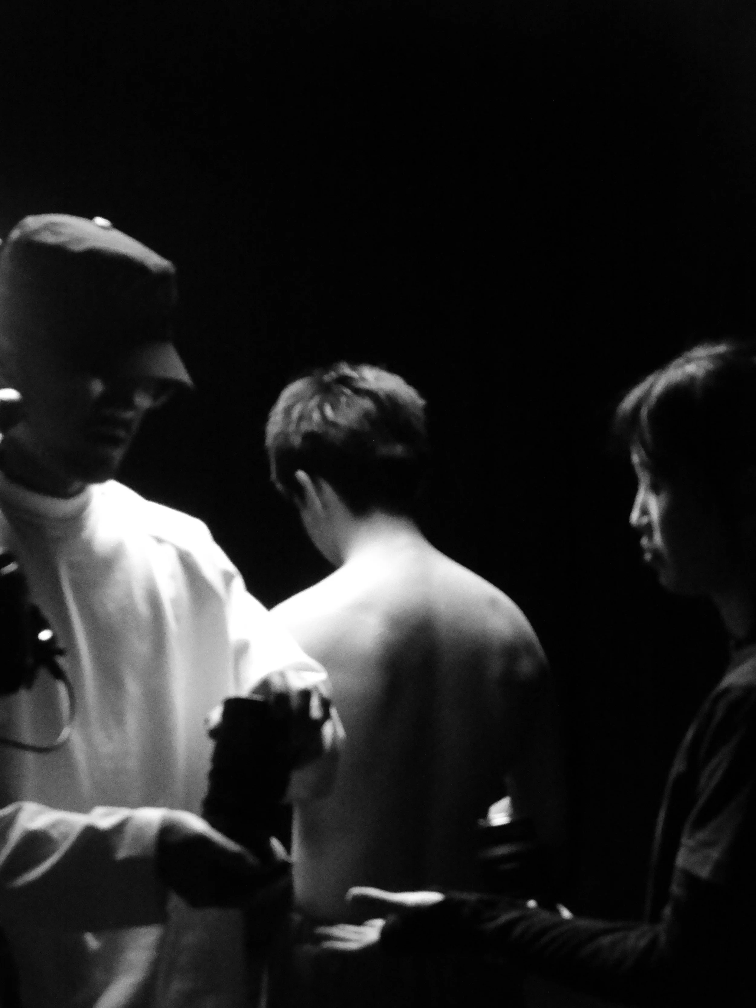 Black-and-white close-up of several people closely gathered in a dimly lit setting.