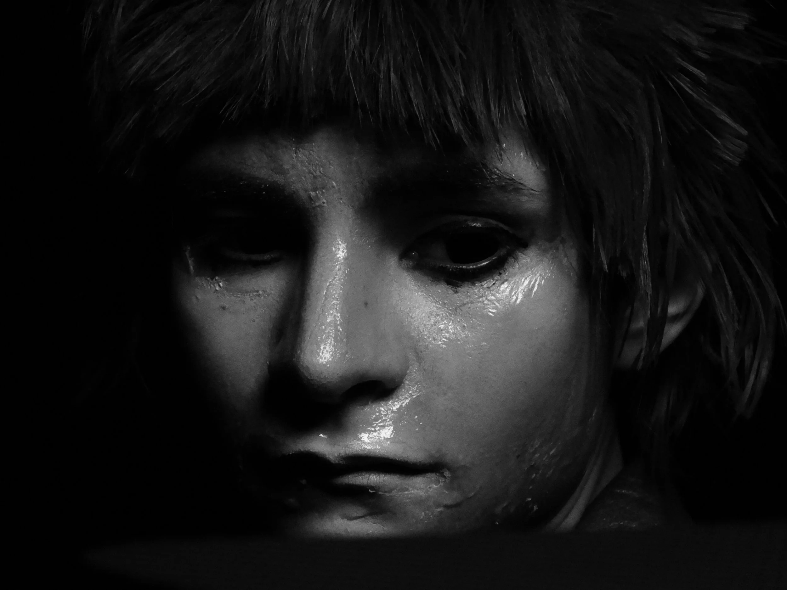 Close-up black-and-white portrait of a person with wet skin, closed eyes, and dark hair