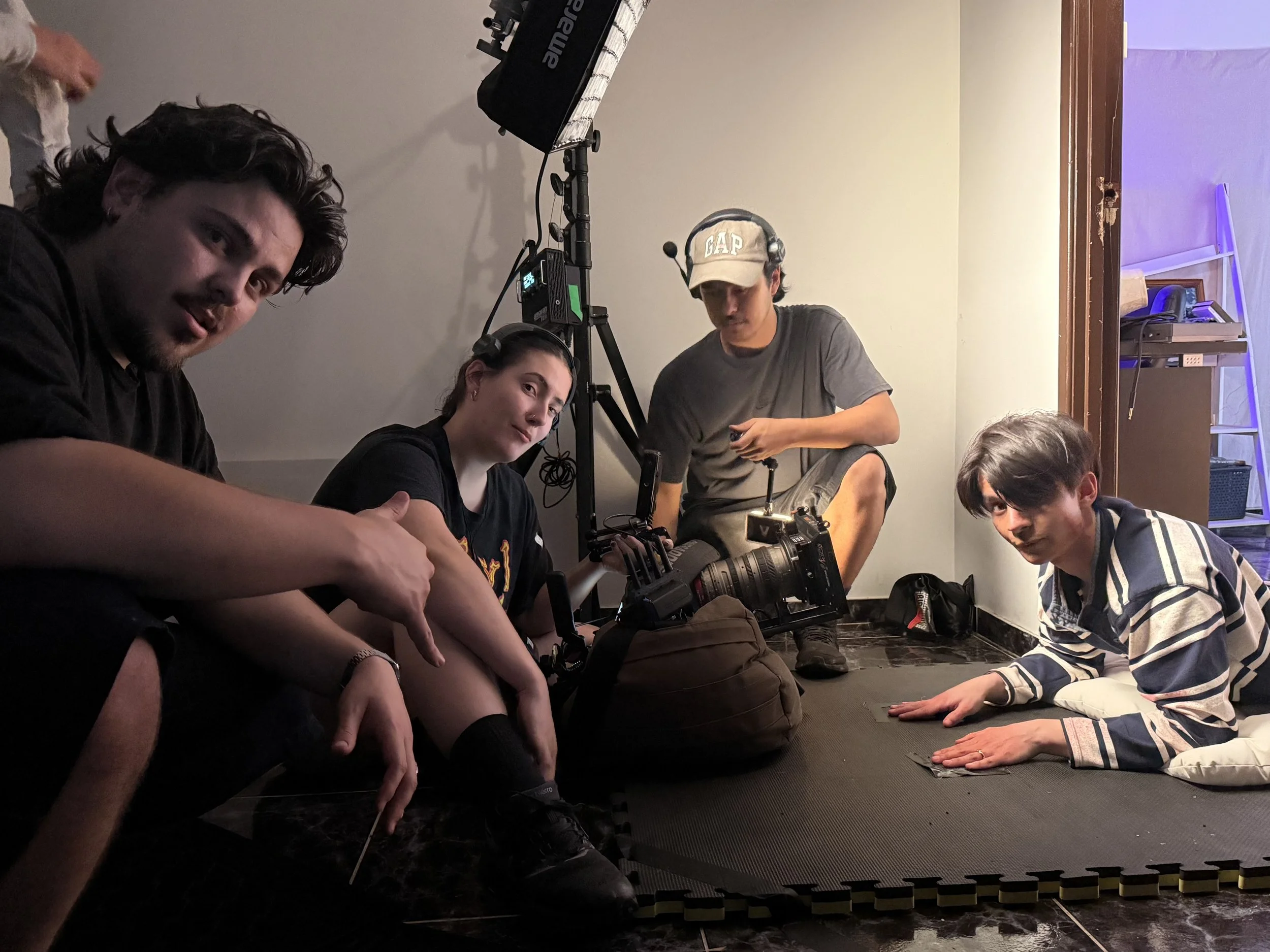 Film crew gathered around a professional cinema camera and lighting equipment indoors