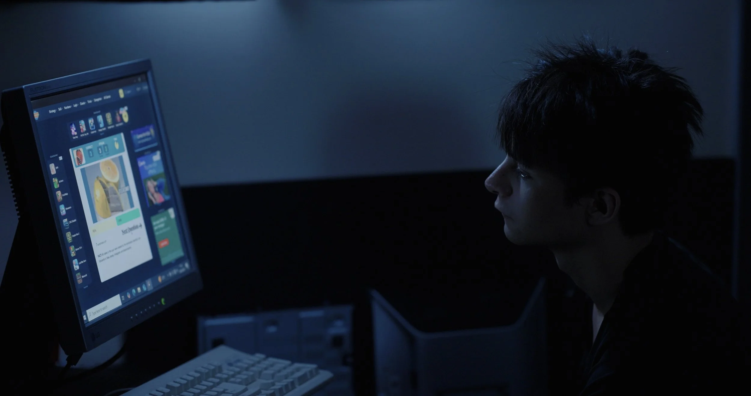 Person viewing a social media website on a computer monitor in a dark room