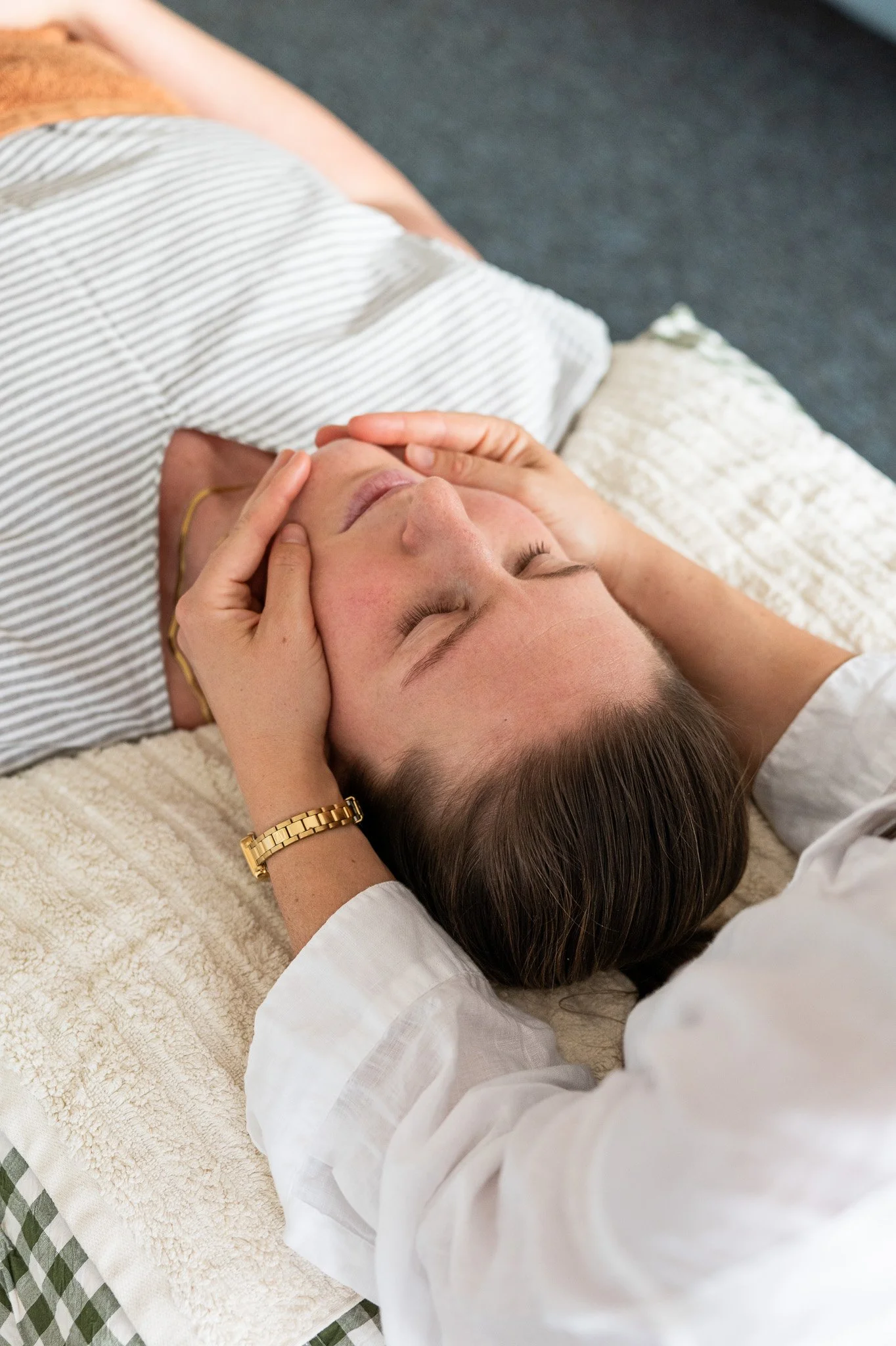 Woman receiving orofacial myology osteopathy while lying on a treatment bed
