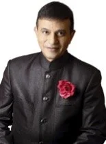 Man in black traditional Indian attire with a pink rose boutonniere