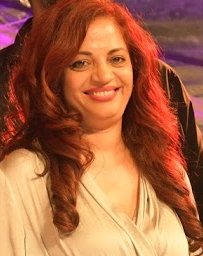 Smiling woman with long auburn hair wearing a cream-colored blouse