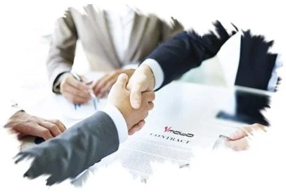 Two people shaking hands across a desk during a business meeting or signing documents.