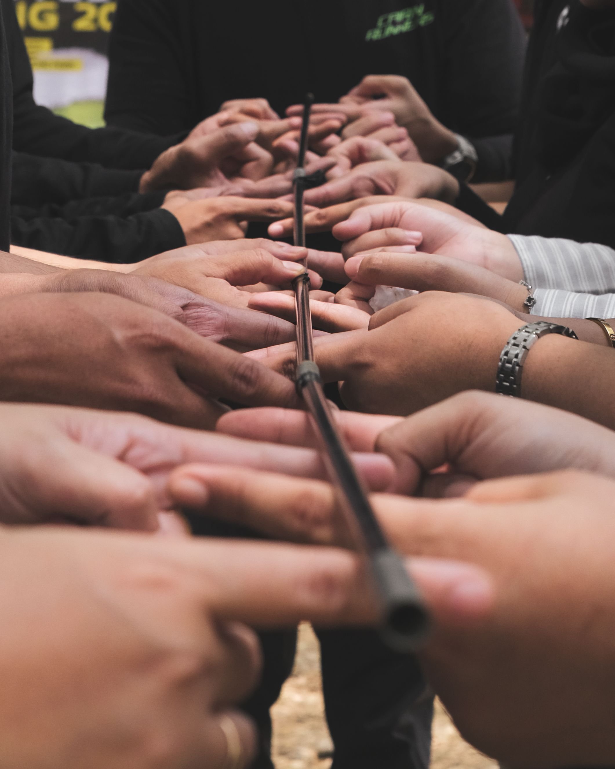 Group of people joining hands around a hockey stick in a team huddle