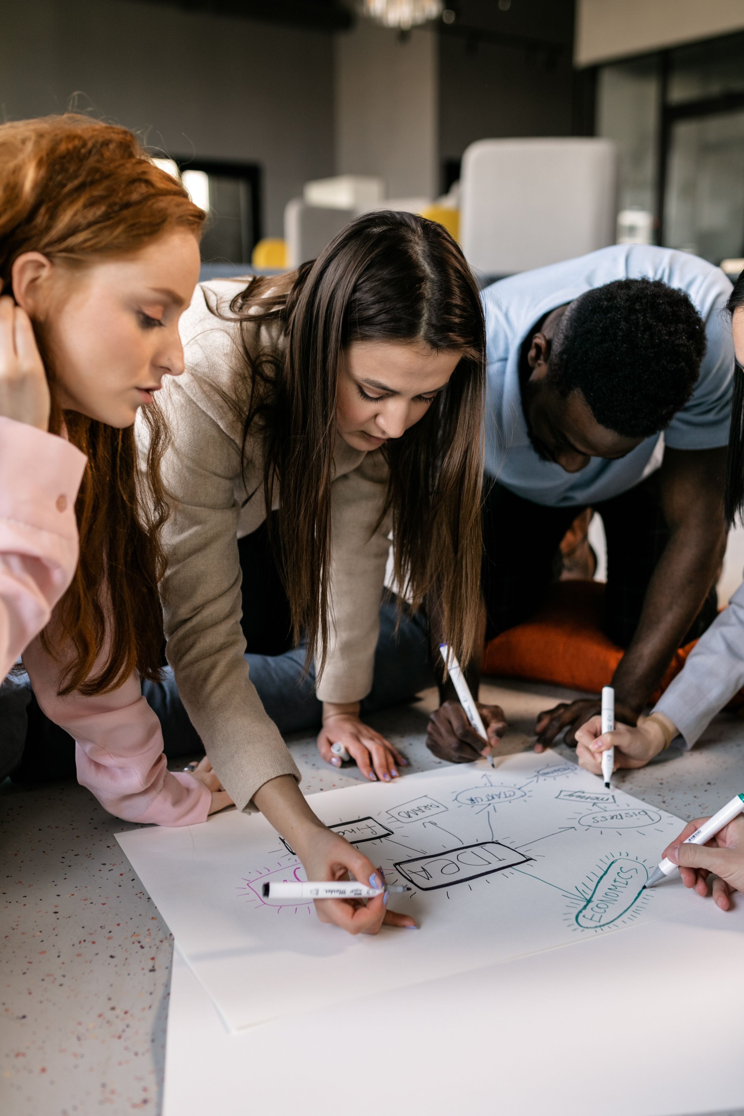 Diverse team collaborating on a business strategy diagram with markers and paper