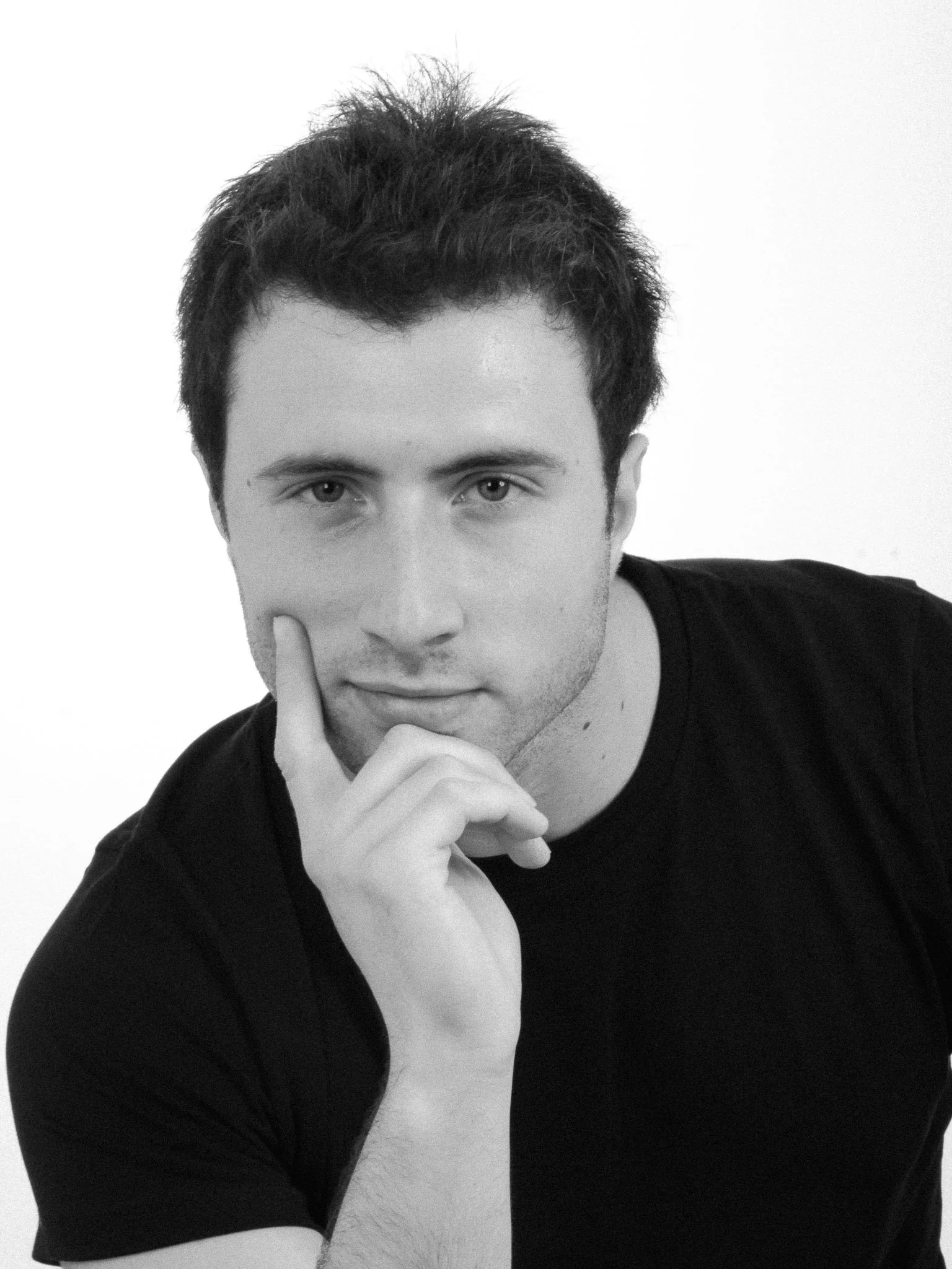 Black-and-white portrait of a thoughtful man resting his chin on his hand