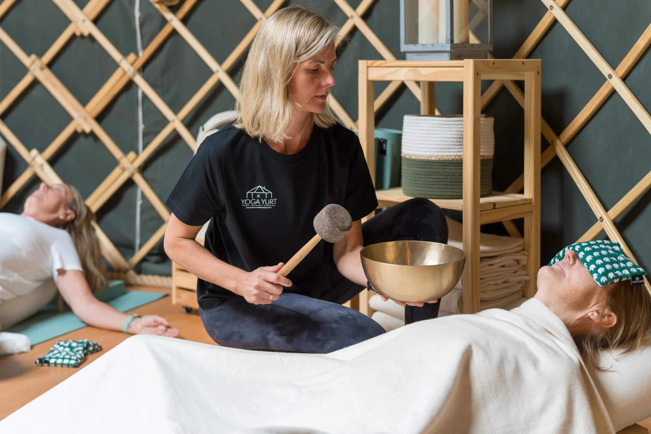 Yoga instructor playing a singing bowl for participants during a sound bath meditation session