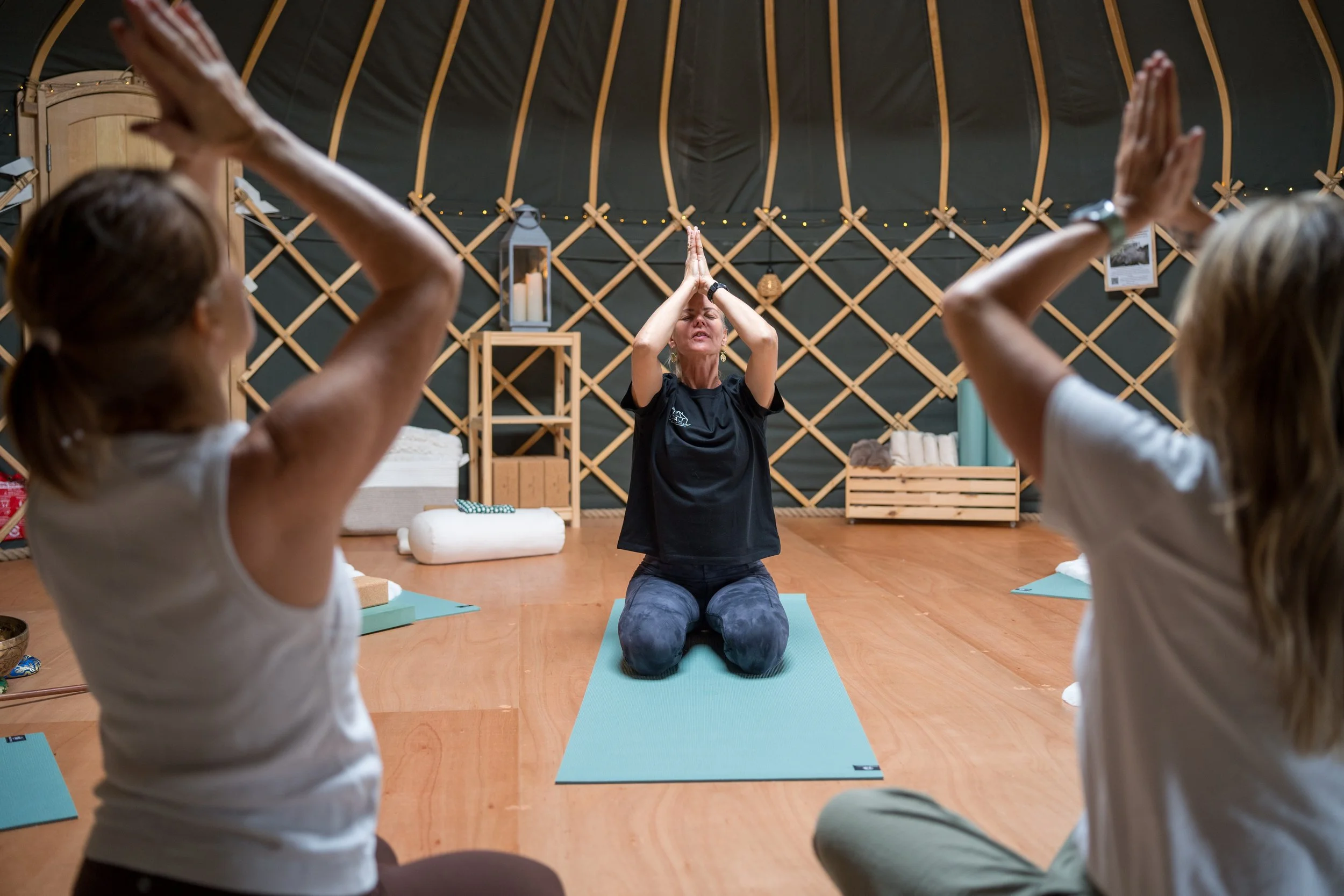 Yoga instructor leading a group meditation inside a cozy yurt studio