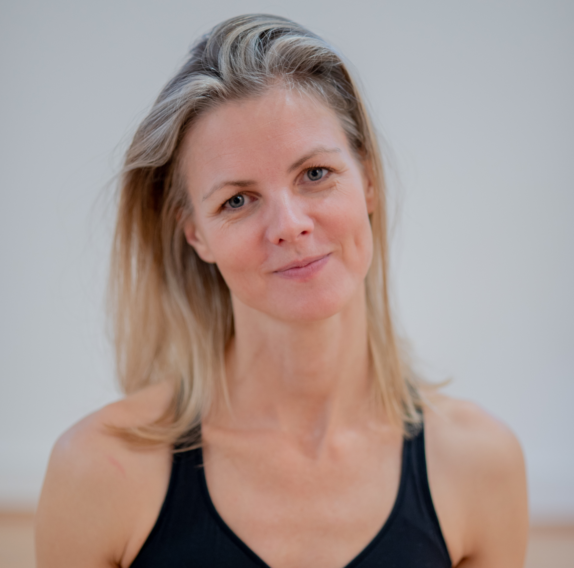 Close-up portrait of a smiling blonde woman wearing a black tank top
